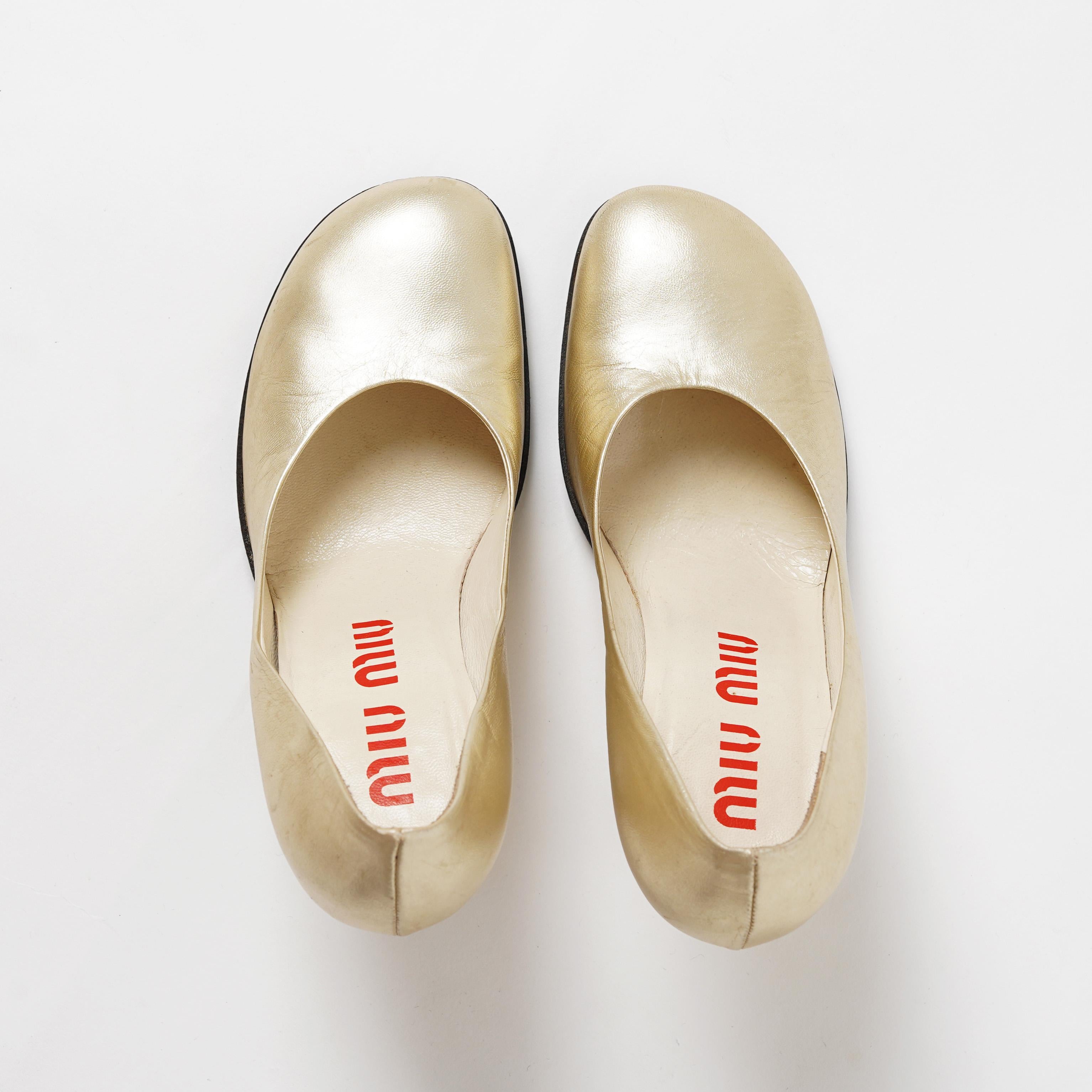Nous vous présentons ces escarpins à talon miroir en métal doré du défilé Miu Miu printemps-été 1998.  Confectionnées dans un cuir lustré d'or pâle aux reflets subtils, ces chaussures présentent un bout carré arrondi, forme emblématique de la