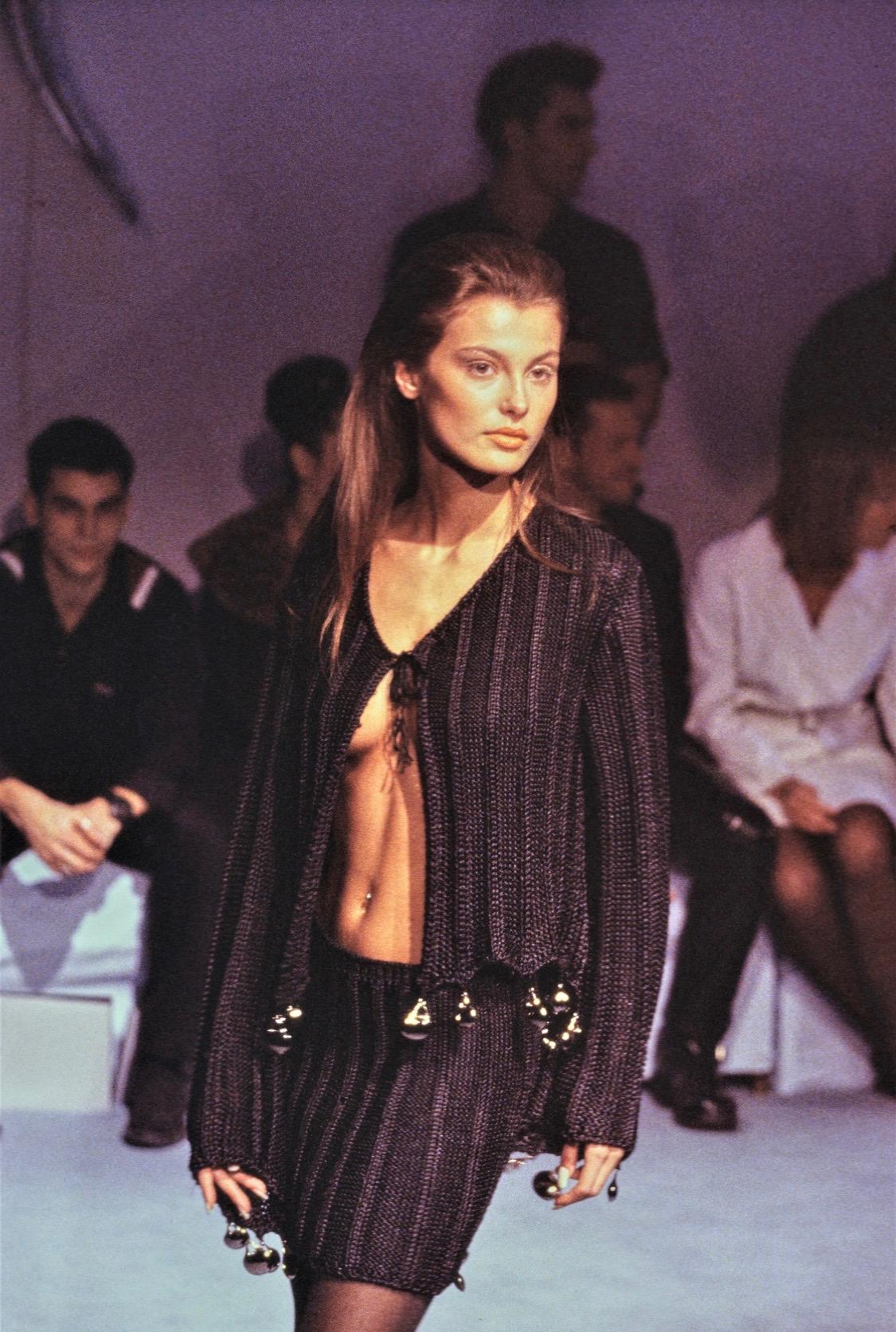 Voici une magnifique robe noire Thierry Mugler, créée par Manfred Mugler. Issue de la collection printemps/été 1998, cette robe présente un décolleté en cœur, des bretelles spaghetti, une jupe de type sirène et des accents argentés au niveau du