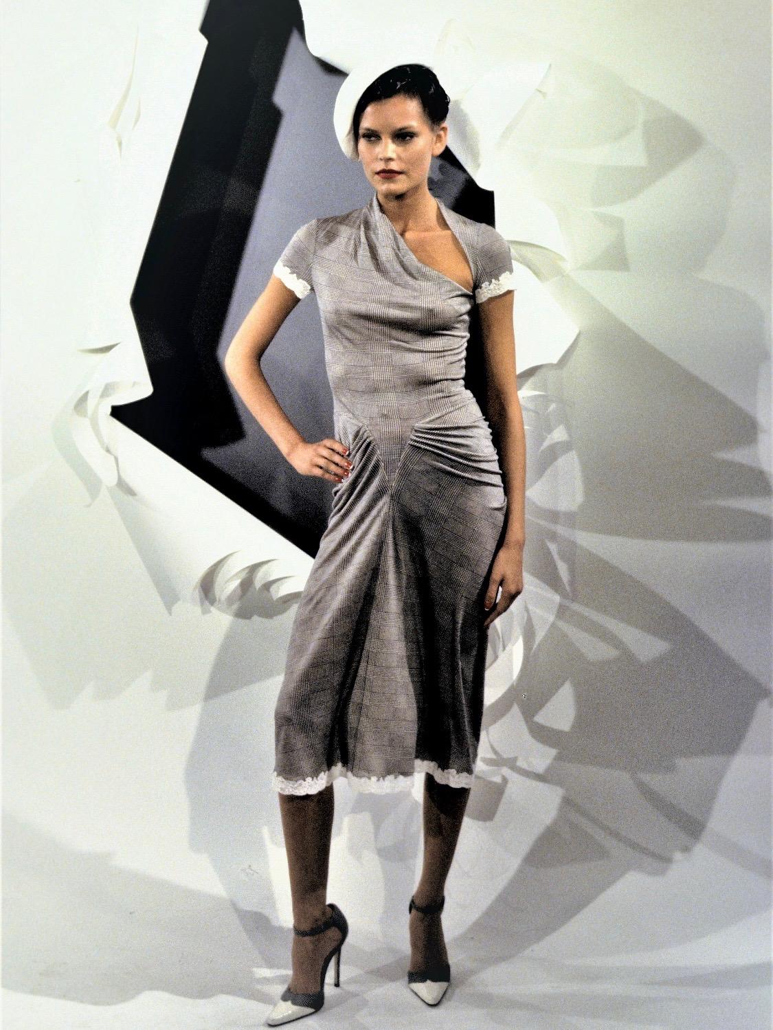 Présentation d'un tailleur jupe bordé de dentelle, conçu par John Galliano pour la collection printemps/été 1999 de Christian Dior. La combinaison du gris et des motifs appliqués en dentelle a fait ses débuts sur le défilé de la Haute Couture