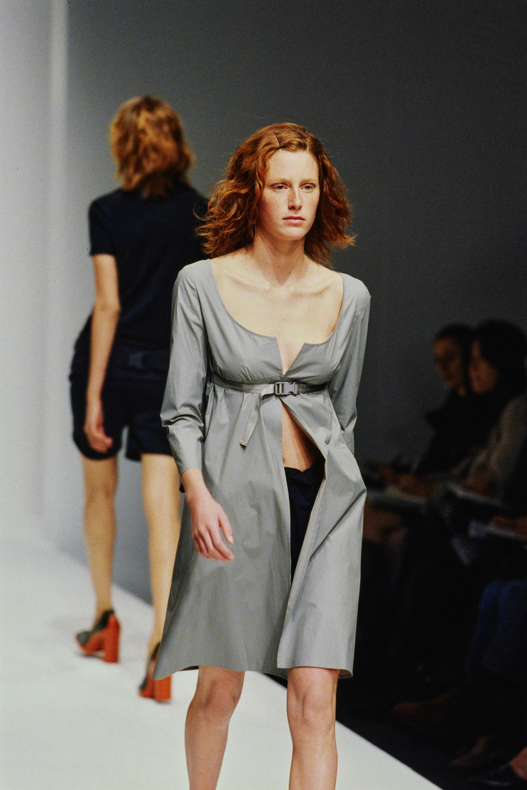 Un pezzo raro e iconico della collezione primavera/estate 1999 di Miu Miu, questo abito tecnico con cintura è un esempio lampante del minimalismo di fine anni '90 interpretato attraverso una sartoria precisa e una forma architettonica. Realizzato in