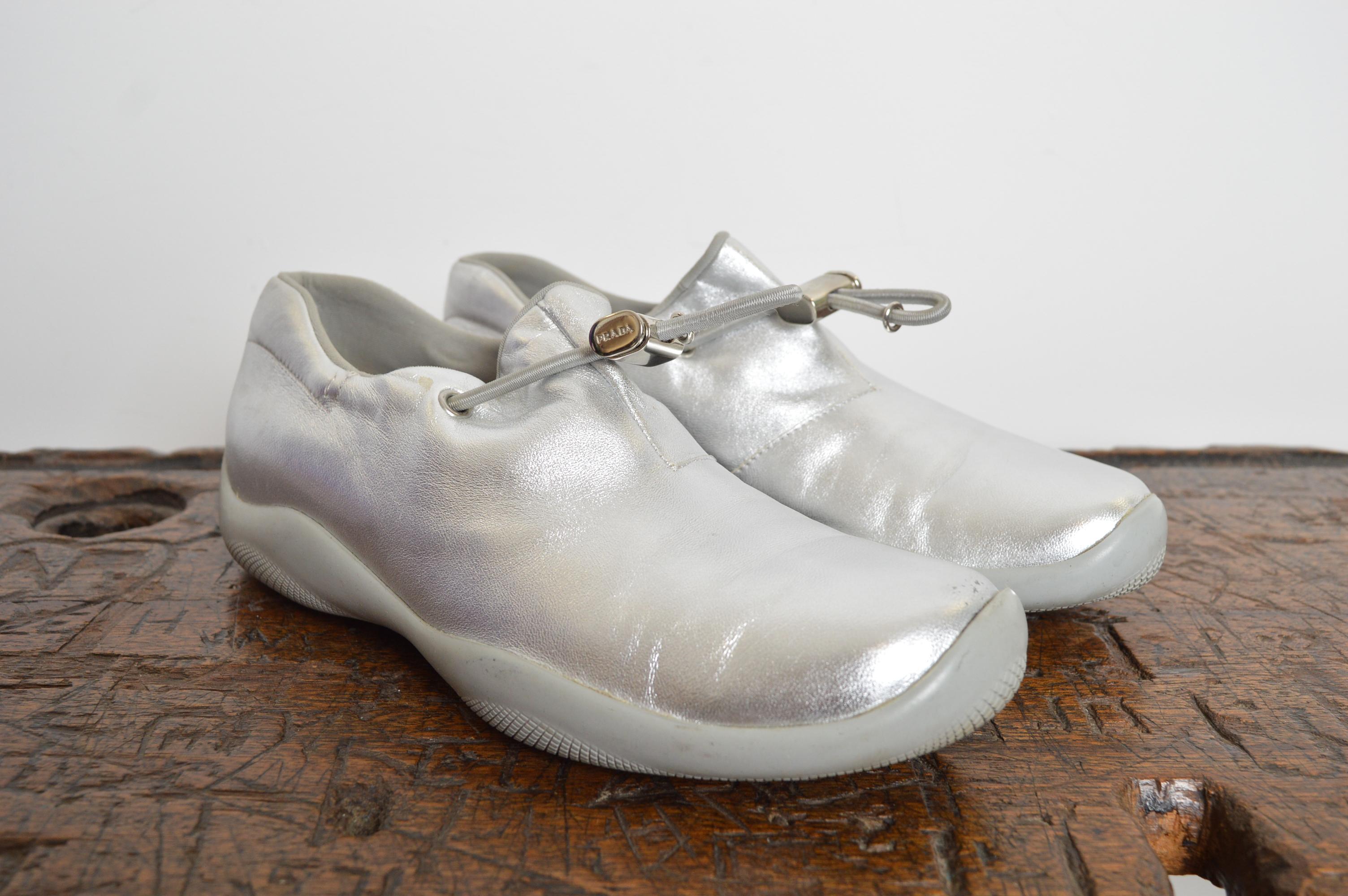Futuristic PRADA Sport, Silver Leather Cups from Spring / Summer 1999. These rare Sneakers feature metallic leather outer with elasticated draw tie detail and chrome Prada buckle.
Size; UK 4.5 / EU 36.5
Condition; 8/10 Fantastic Used Condition, with