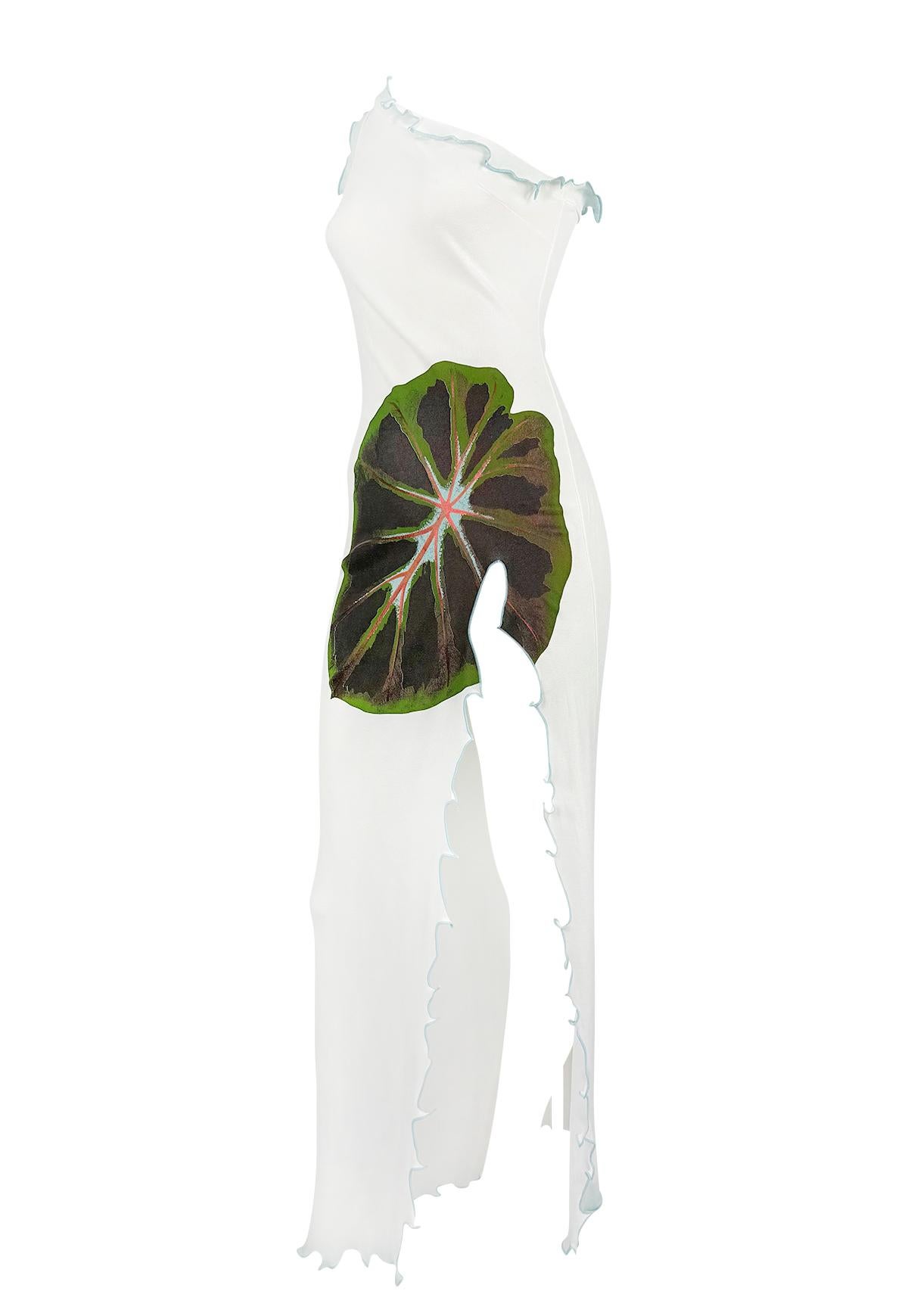 From Christian Lacroix’s Spring/Summer 2000 collection, this white maxi dress showcases an asymmetrical silhouette accented with delicate blue ruffle trim. A bold screen-printed leaf motif wraps around the hip, drawing attention to the dramatic