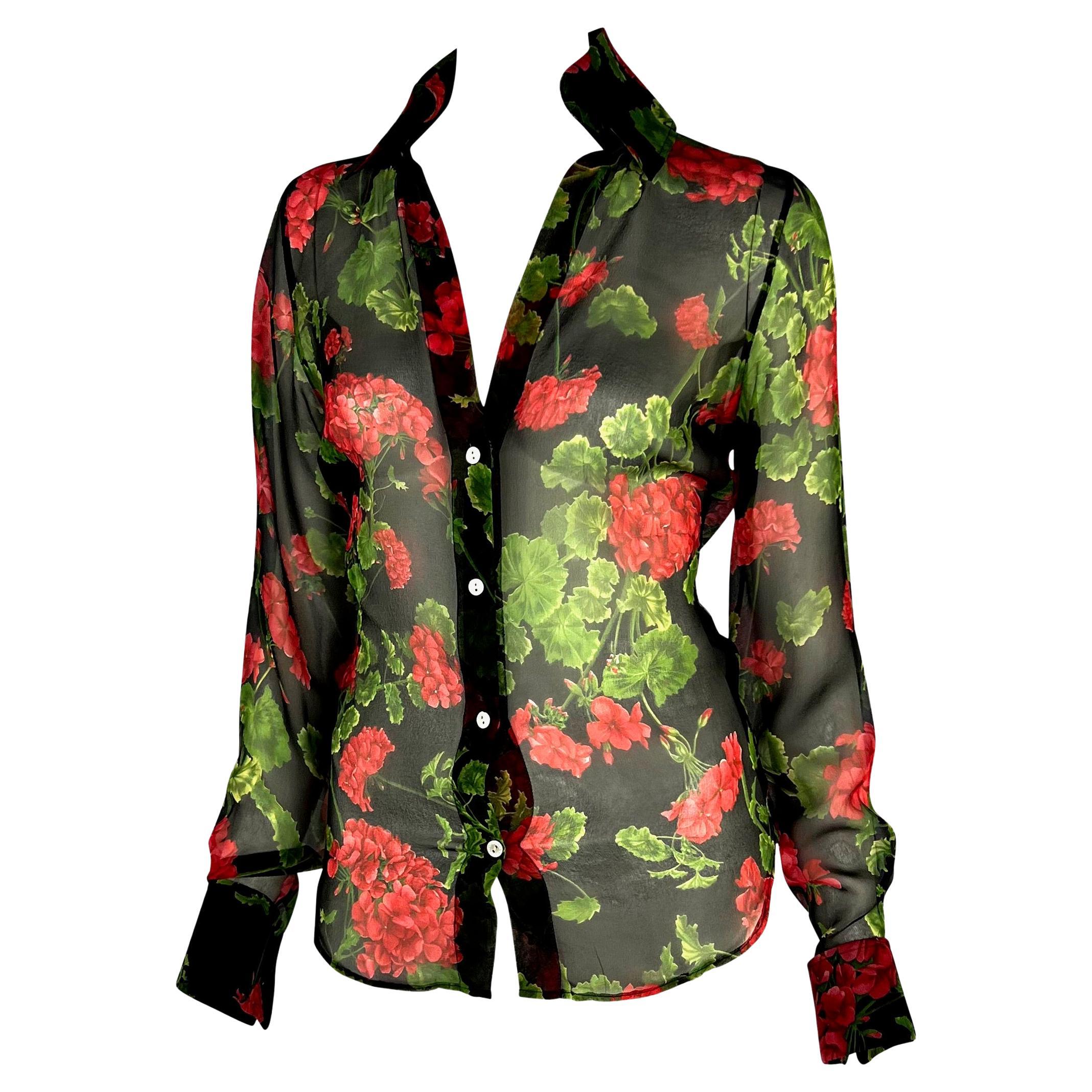 Présentation d'une chemise boutonnée Dolce and Gabbana à fleurs transparentes. Issue de la collection Printemps/Eté 2000, cette chemise semi-transparente est recouverte d'hortensias rouges sur fond noir. Le haut a un décolleté plongeant et ne se