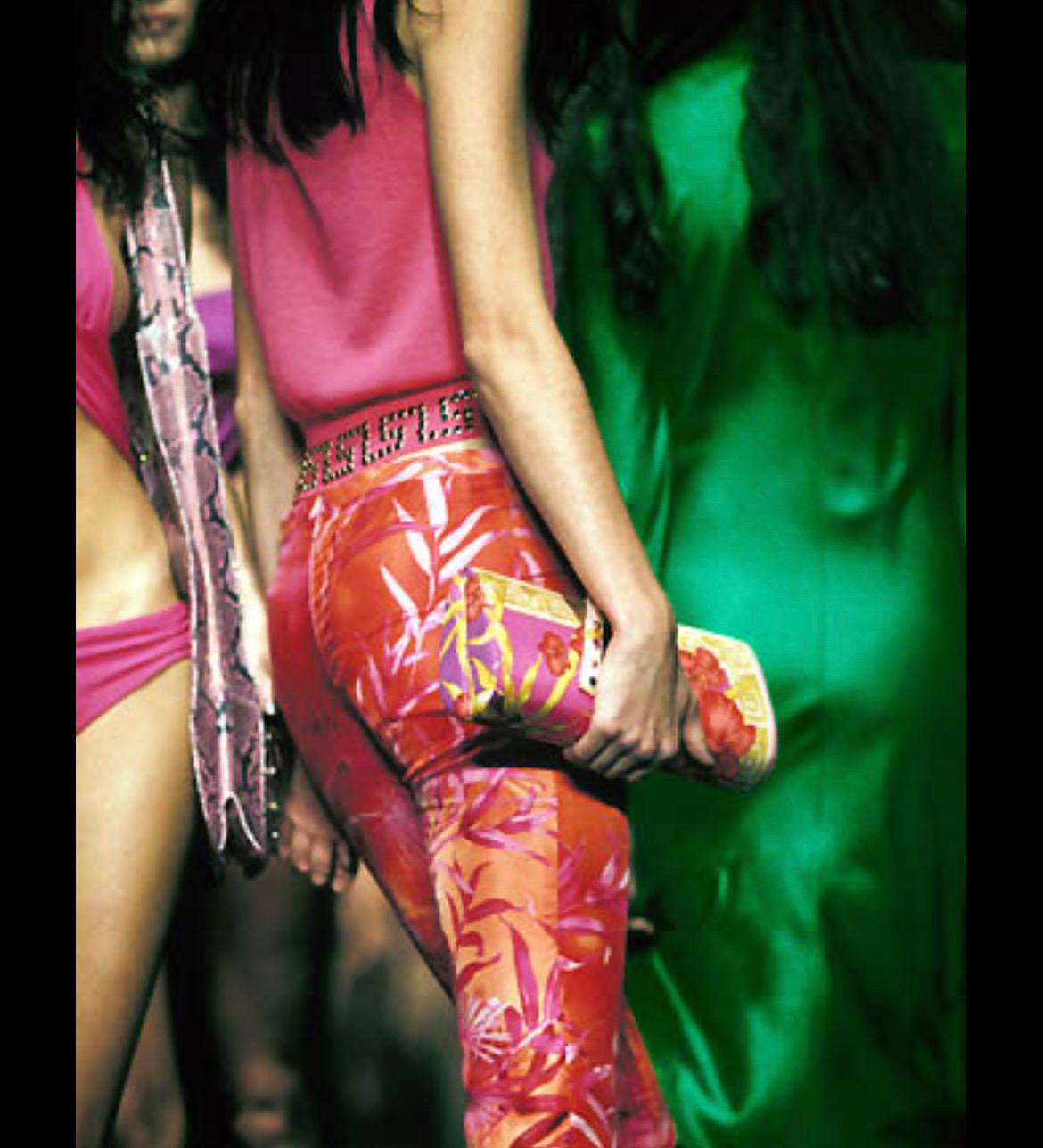 Diese atemberaubende, wandelbare Clutch von Versace ist mit einem rosafarbenen Dschungelprint aus Seide versehen. Vorne und in der Mitte akzentuiert eine verspiegelte goldene Medusa-Plakette den Schnappverschluss. Donatella entwarf diese wandelbare