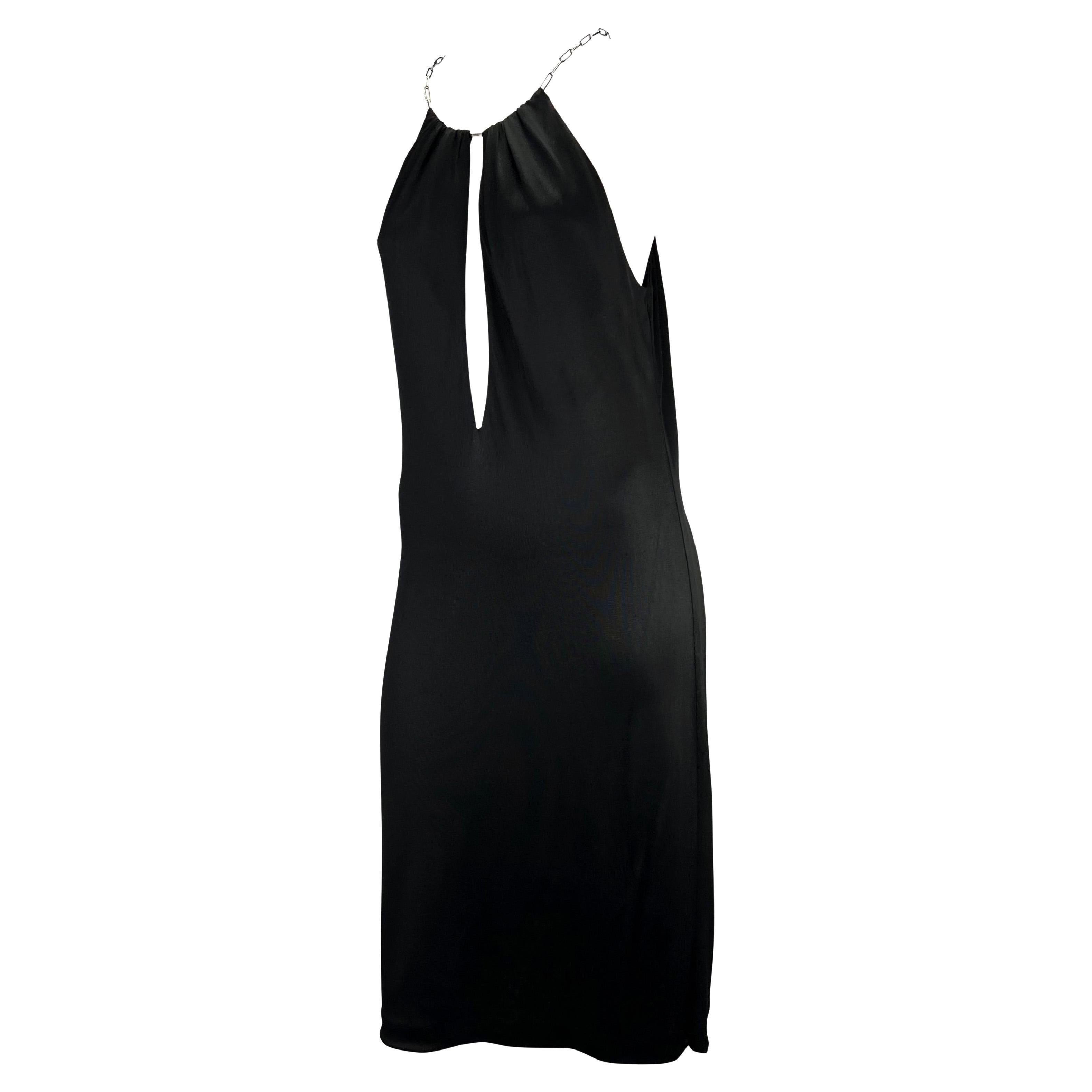 Présentation d'une magnifique robe plongeante Gucci, dessinée par Tom Ford. Issue de la collection Printemps/Été 2000, cette robe est suspendue à un collier en maillons de chaîne argentés. Conçue en viscose noire, cette robe se drape parfaitement