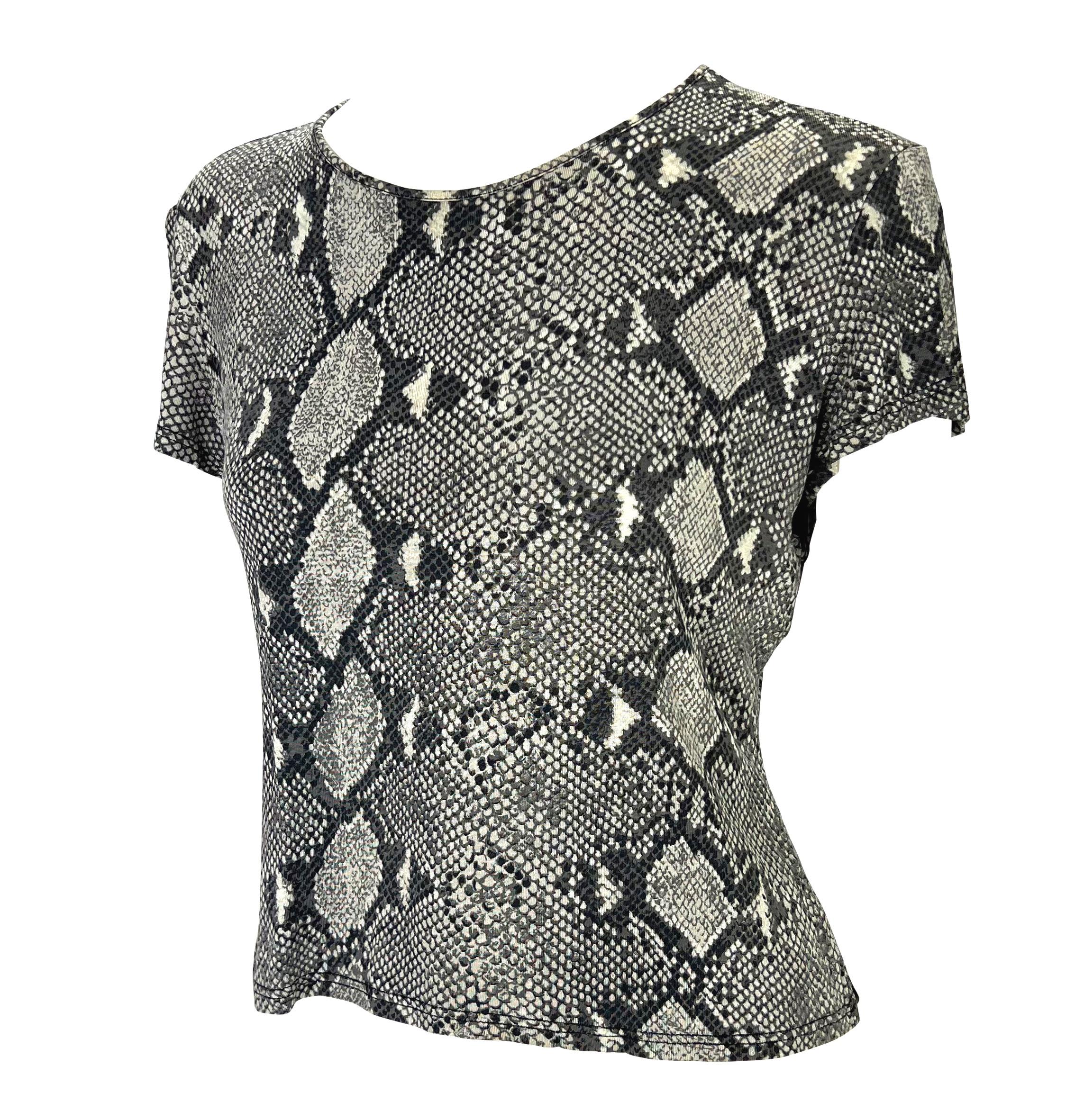 Voici un t-shirt Gucci gris imprimé peau de serpent, dessiné par Tom Ford. Issu de la collection printemps/été 2000, le défilé de la saison était recouvert de l'imprimé peau de serpent identique à celui de ce t-shirt. Cette chemise entièrement en