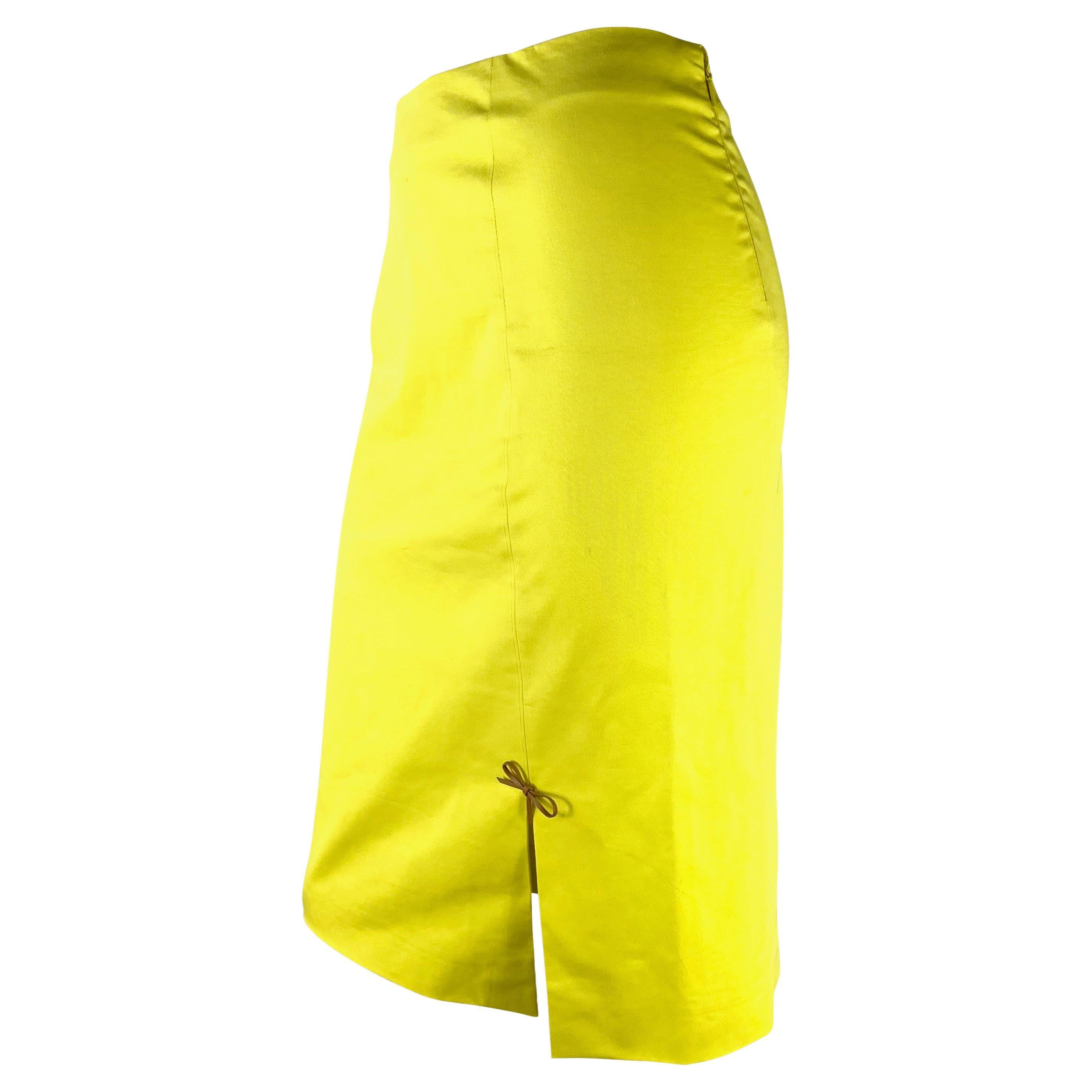 Presenting a bright yellow Gucci skirt, designed by Tom Ford. From the Spring/Summer 2000 collection, this pencil-style skirt features a slit at the front made complete with a small tan leather bow. 

Approximate measurements:
Size - IT40
28