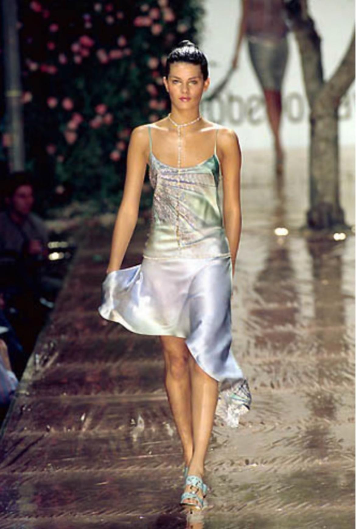 Roberto Cavalli präsentiert eine goldfarbene, mit Strasssteinchen besetzte Körperkette. Aus der Frühjahr/Sommer-Kollektion 2000 debütierte diese Kostüm-Körperkette auf dem Laufsteg der Saison mit ähnlichen Versionen in mehreren Looks. Diese schicke