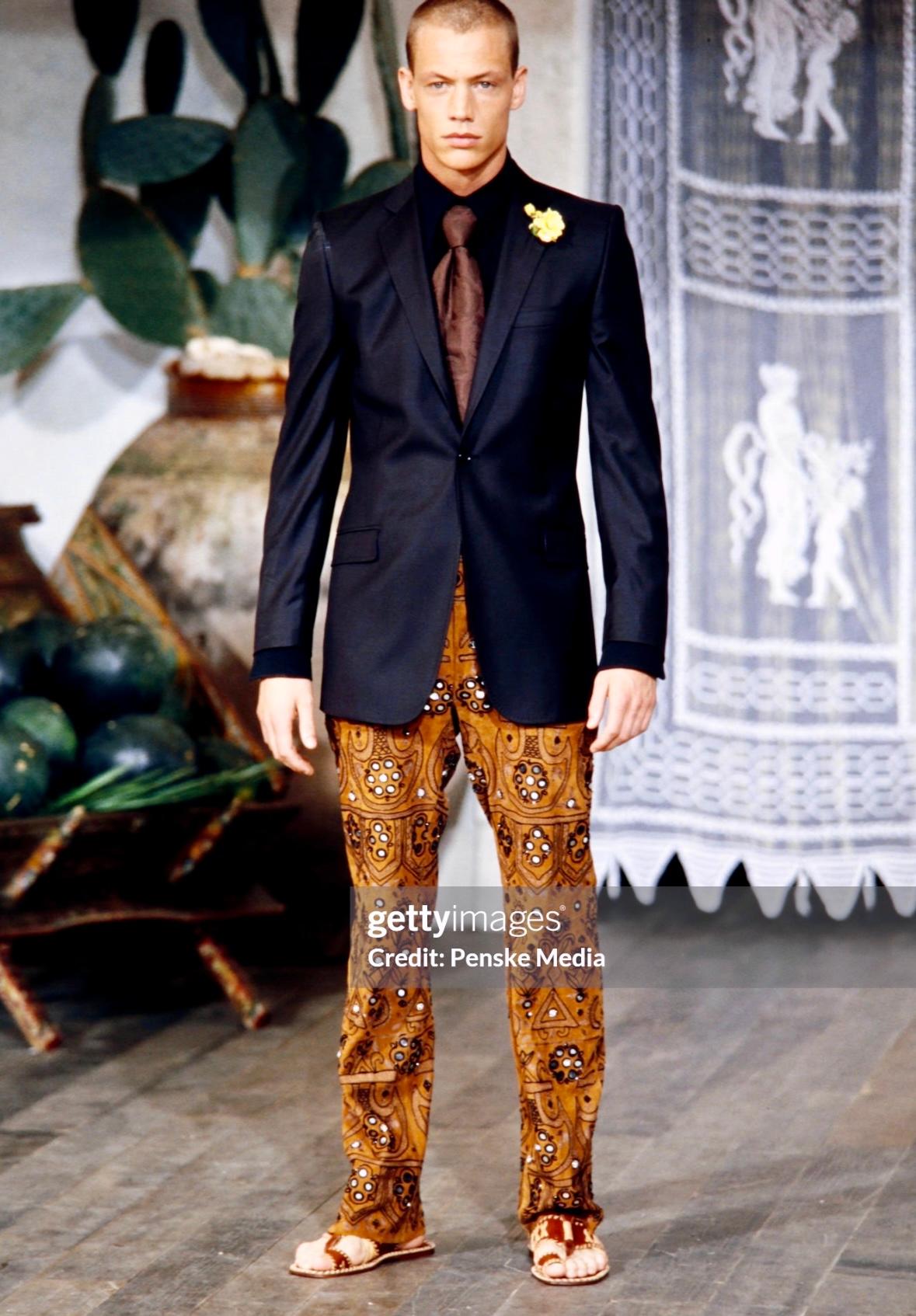 Presenting a pair of tan embellished Dolce & Gabbana suede pants. From the Spring/Summer 2001 collection, nearly identical pants debuted on the season's men's runway. Constructed entirely of tan suede, these pants feature a high waist and flare cut.