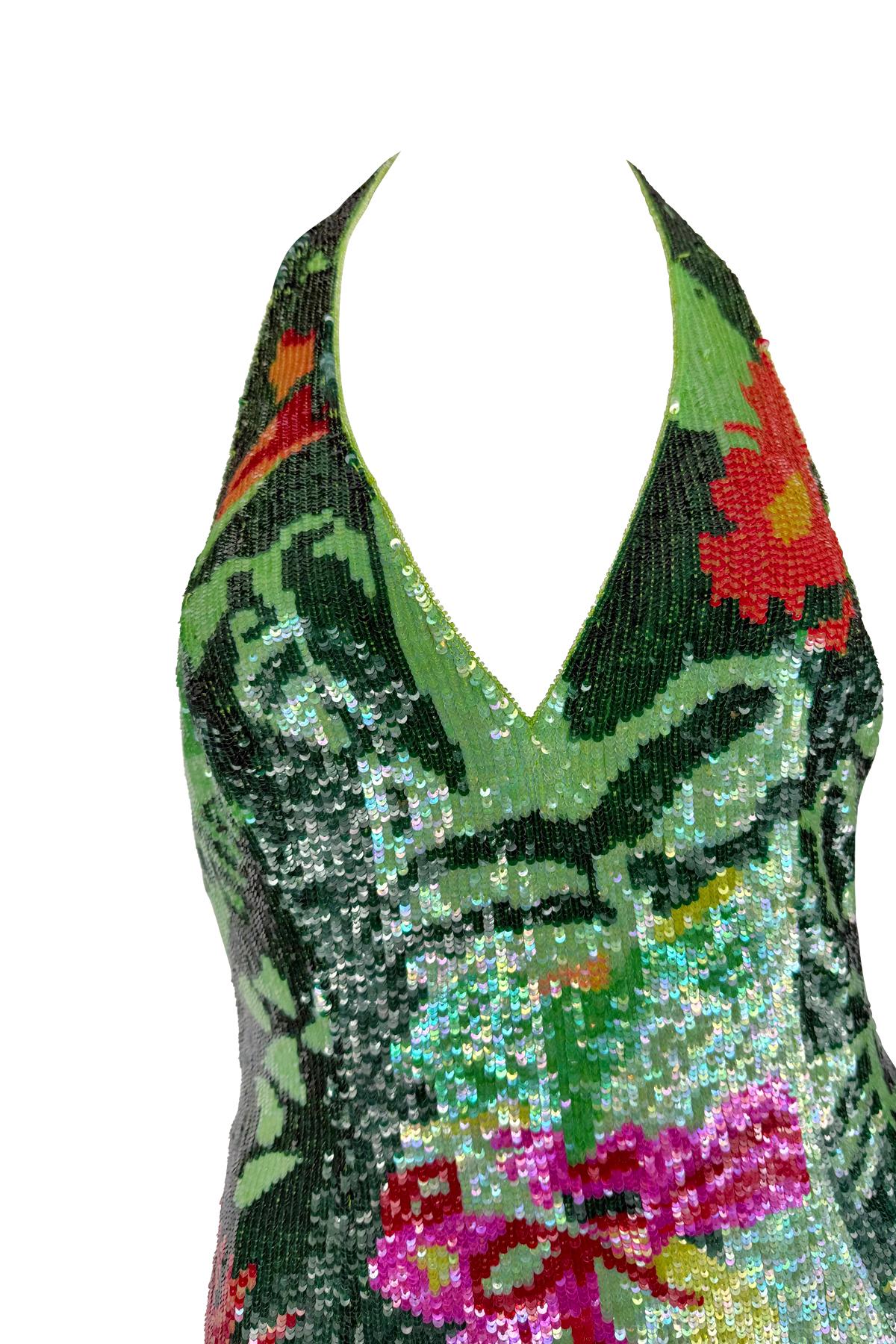 From Escada’s Spring/Summer 2001 collection, this vibrant halter dress is covered entirely in shimmering green sequins and adorned with a bold tropical floral motif in tones of fuchsia, red, orange, and yellow. Featuring a plunging neckline and open