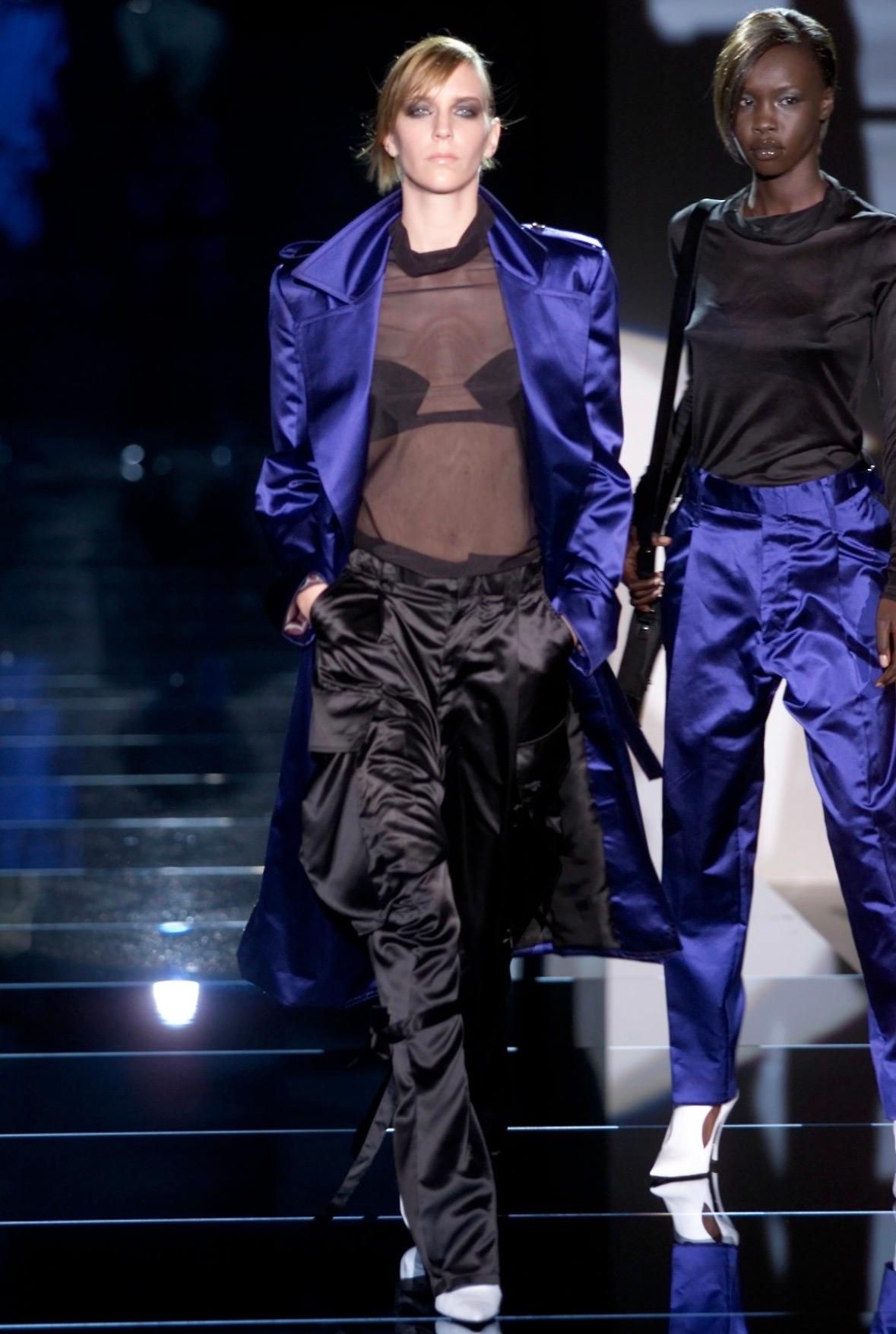 This pair of black satin pants by Gucci, designed by Tom Ford for the Spring/Summer 2001 collection, debuted on the runway as look 5, modeled by Hannelore Knuts. These high-waisted, extra-wide leg pants feature a glossy satin construction, large