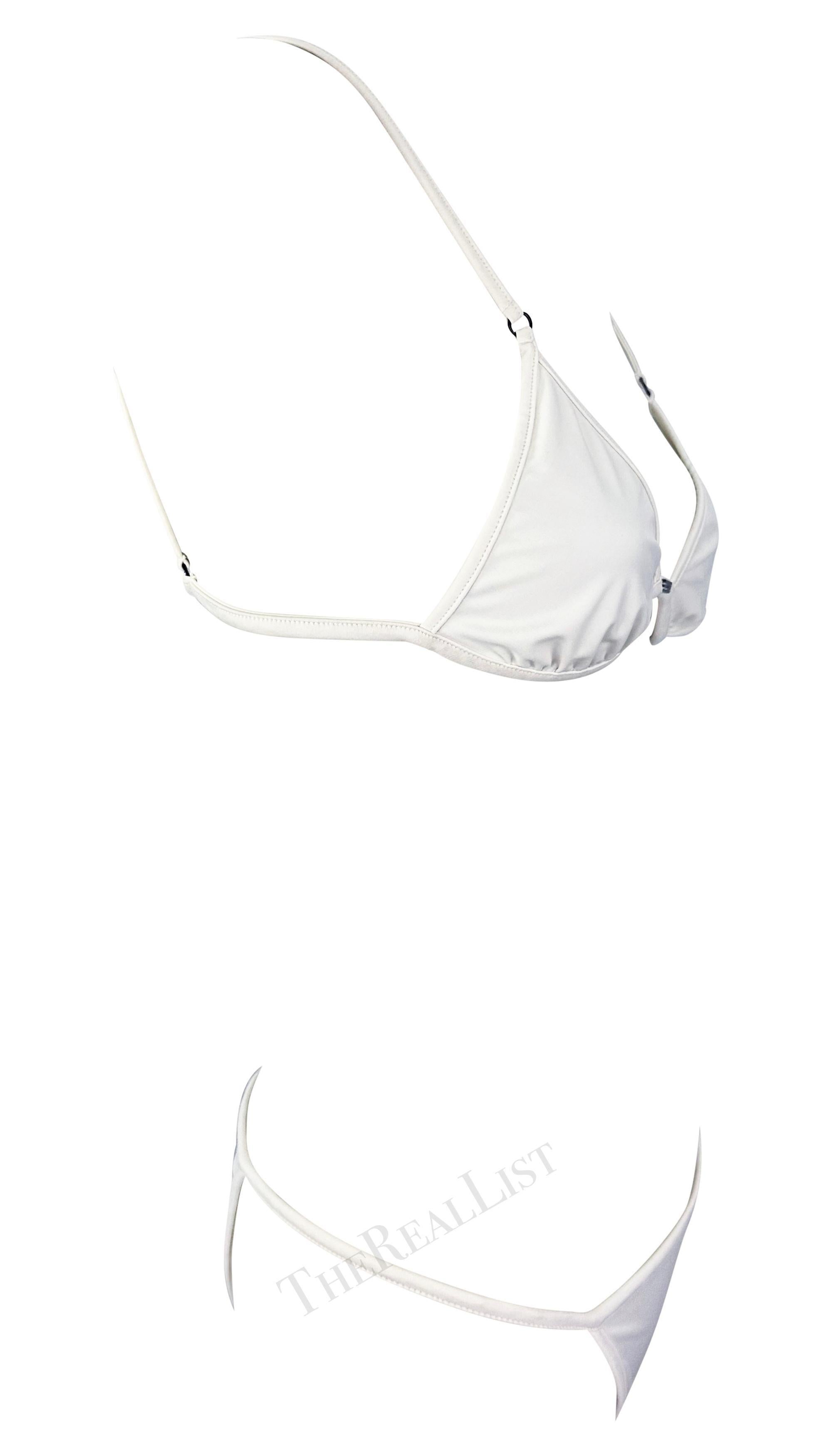 Te presentamos un elegante bikini blanco de Gucci, diseñado por Tom Ford. De la colección Primavera/Verano 2001, este bañador blanco de dos piezas se compone de un top estilo triángulo y un pantalón de tirantes finos. La parte superior lleva una