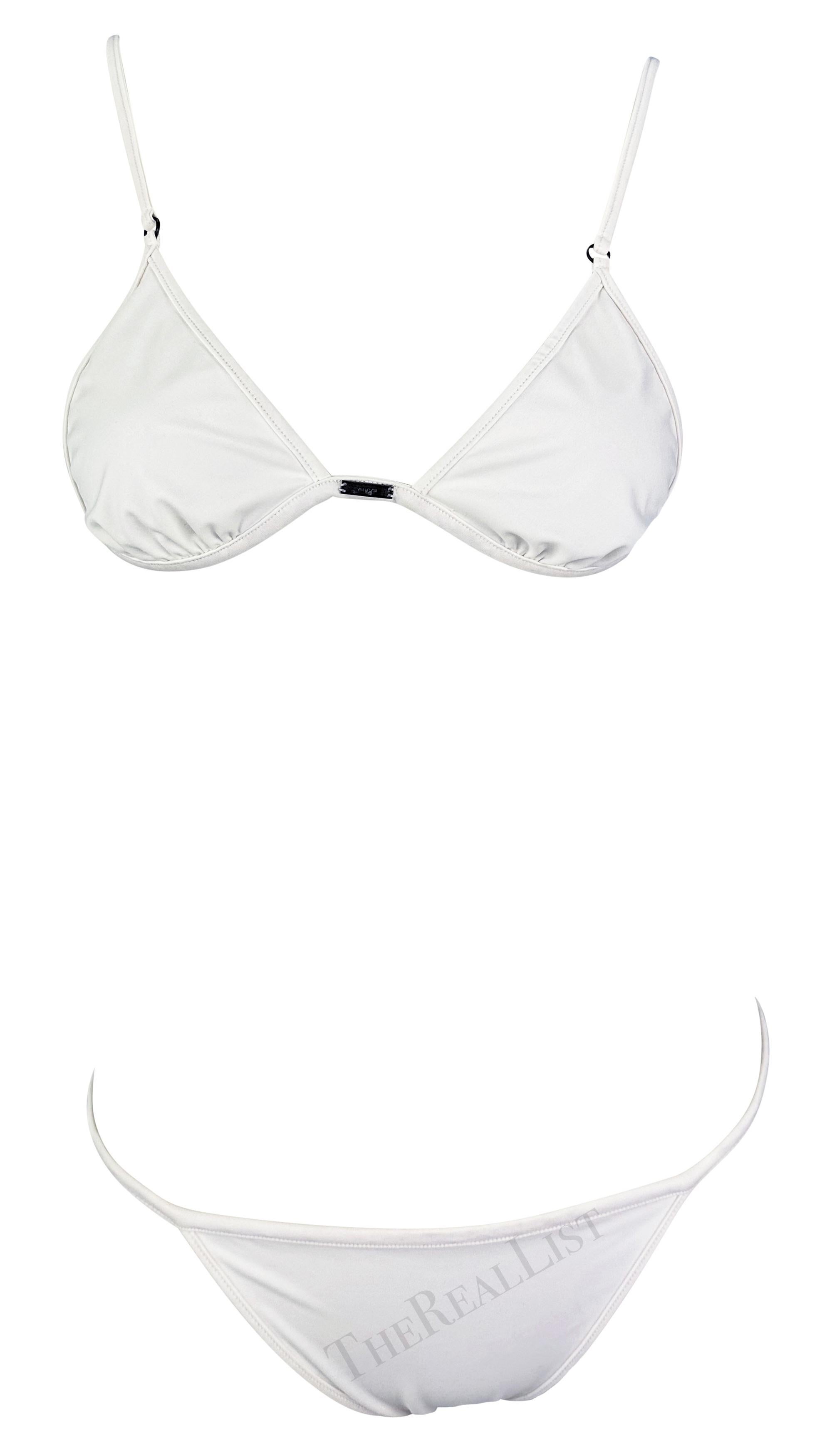 Sie präsentiert einen schicken weißen Gucci-Bikini, entworfen von Tom Ford. Dieser weiße Zweiteiler aus der Frühjahr/Sommer-Kollektion 2001 besteht aus einem dreieckigen Oberteil und einem dünnen Unterteil mit Schnüren. Das Oberteil verfügt über