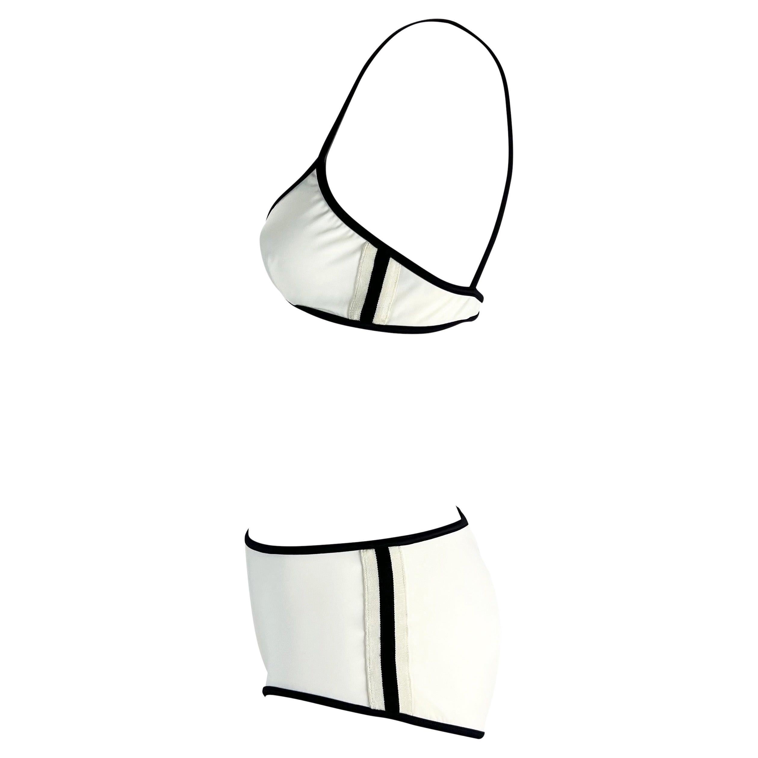 This chic Gucci bikini set, designed by Tom Ford, is from the Spring/Summer 2001 collection. The set features a triangle top and boy-short bottoms, both in a simple white with black vertical stripes on the sides. The top is secured with a silver