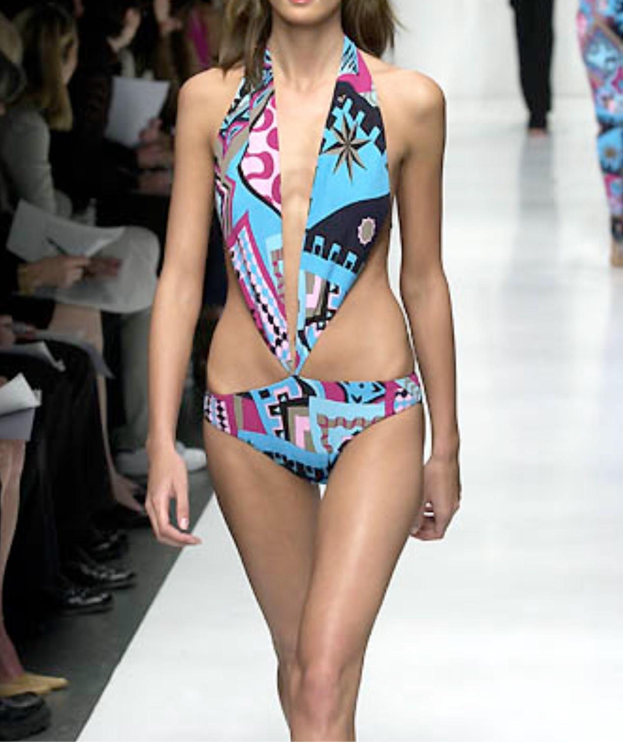 Este bañador de una pieza Yigal Azrouël de la colección Primavera/Verano 2001 tiene un escote halter pronunciado y un atrevido estampado gráfico inspirado en los años 60 en tonos rosa, azul y negro. Como se vio en la pasarela de la temporada, la