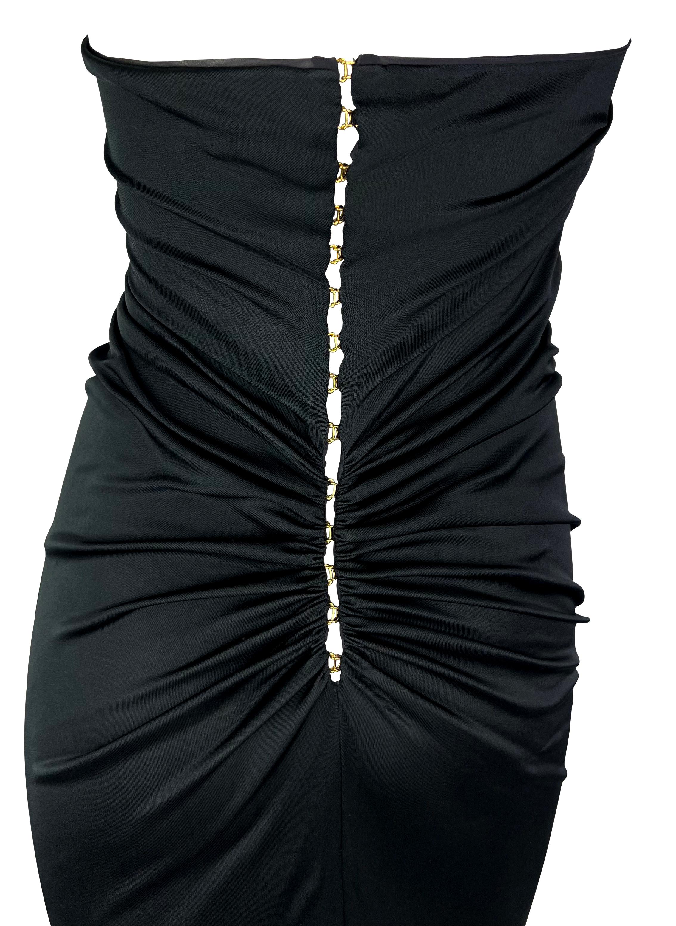 This black strapless Yves Saint Laurent dress, designed by Tom Ford for the Spring/Summer 2001 collection, features a series of gold-tone hook closures at the back, creating a gentle ruching effect that dissipates at the front. This midi-length