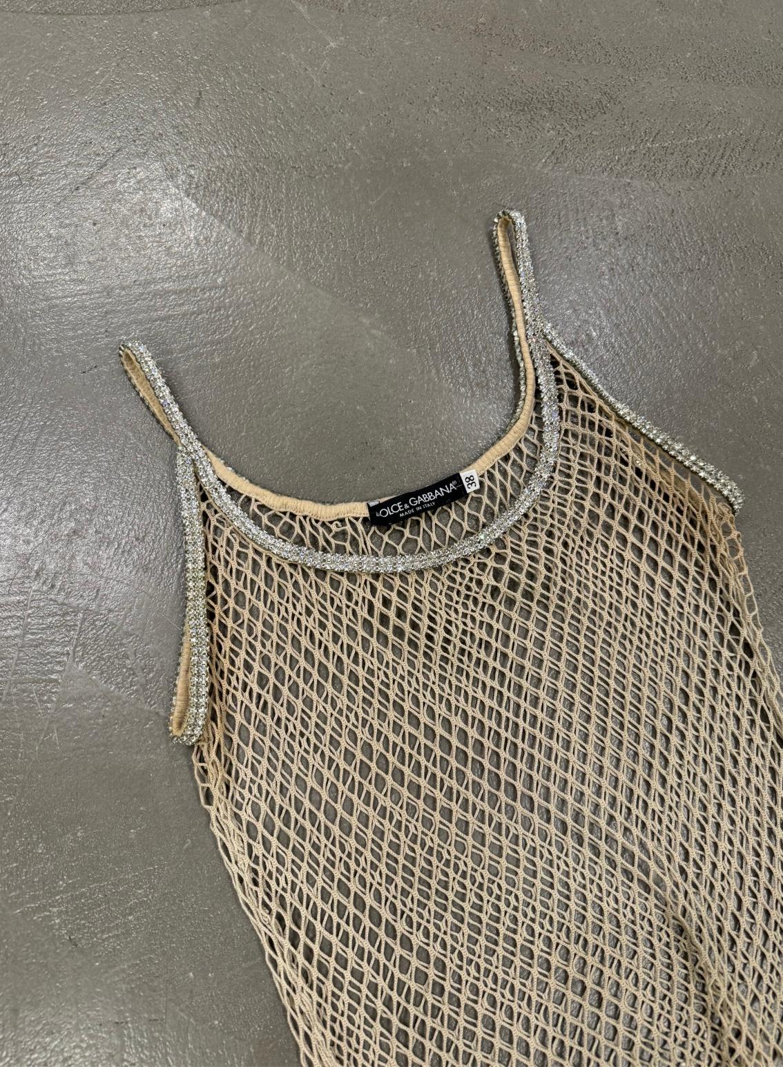 Top a rete Swarovski Dolce & Gabbana J-Lo, P/E 2002

Questo rarissimo top di Dolce & Gabbana della collezione Primavera/Estate 2002 è un pezzo iconico dell'anno 2000, indossato notoriamente da Jennifer Lopez. Fabrice di un delicato tessuto a rete