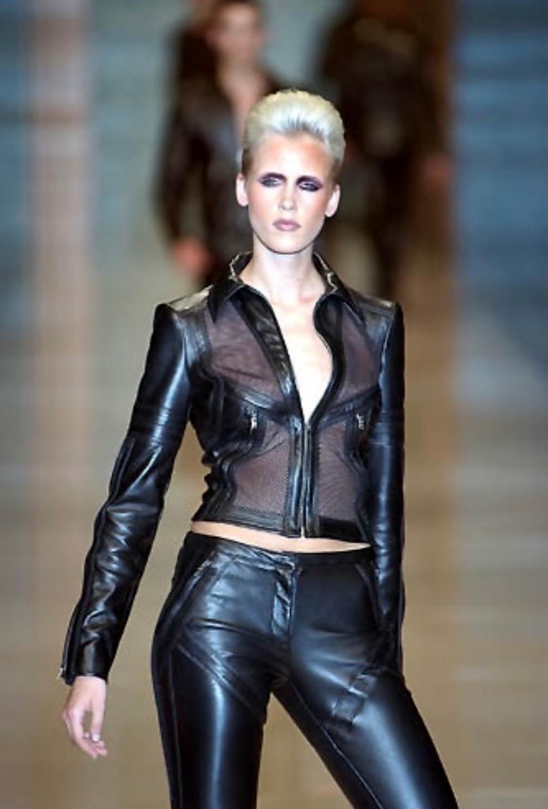 Présentation d'une veste courte en maille noire Gianni Versace, dessinée par Donatella Versace. Issue de la collection printemps/été 2002, cette superbe veste noire présente des panneaux de maille sur le devant et dans le dos. Le manteau est