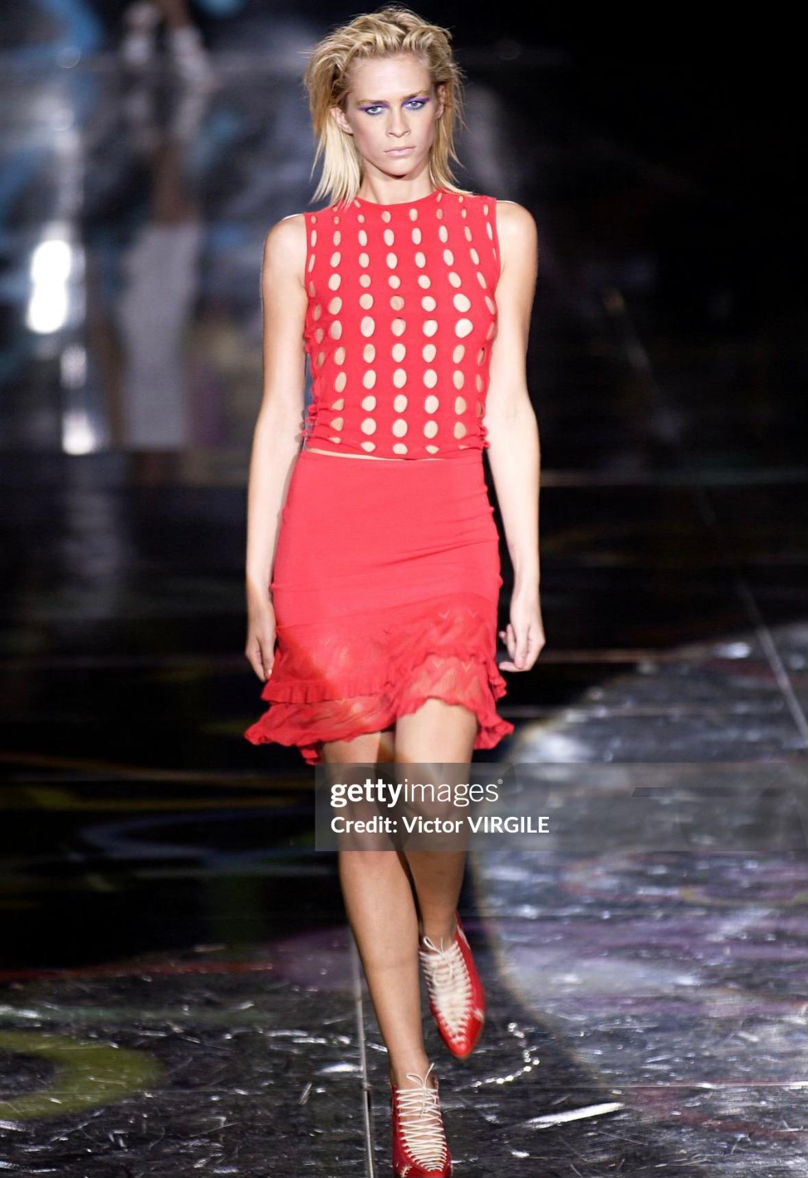 Disegnato da Donatella Versace for Gianni Versace per la sua collezione primavera/estate 2002, una versione di questo top aderente di colore rosso acceso ha debuttato sulla passerella della stagione come parte del look 10. Questo top elasticizzato