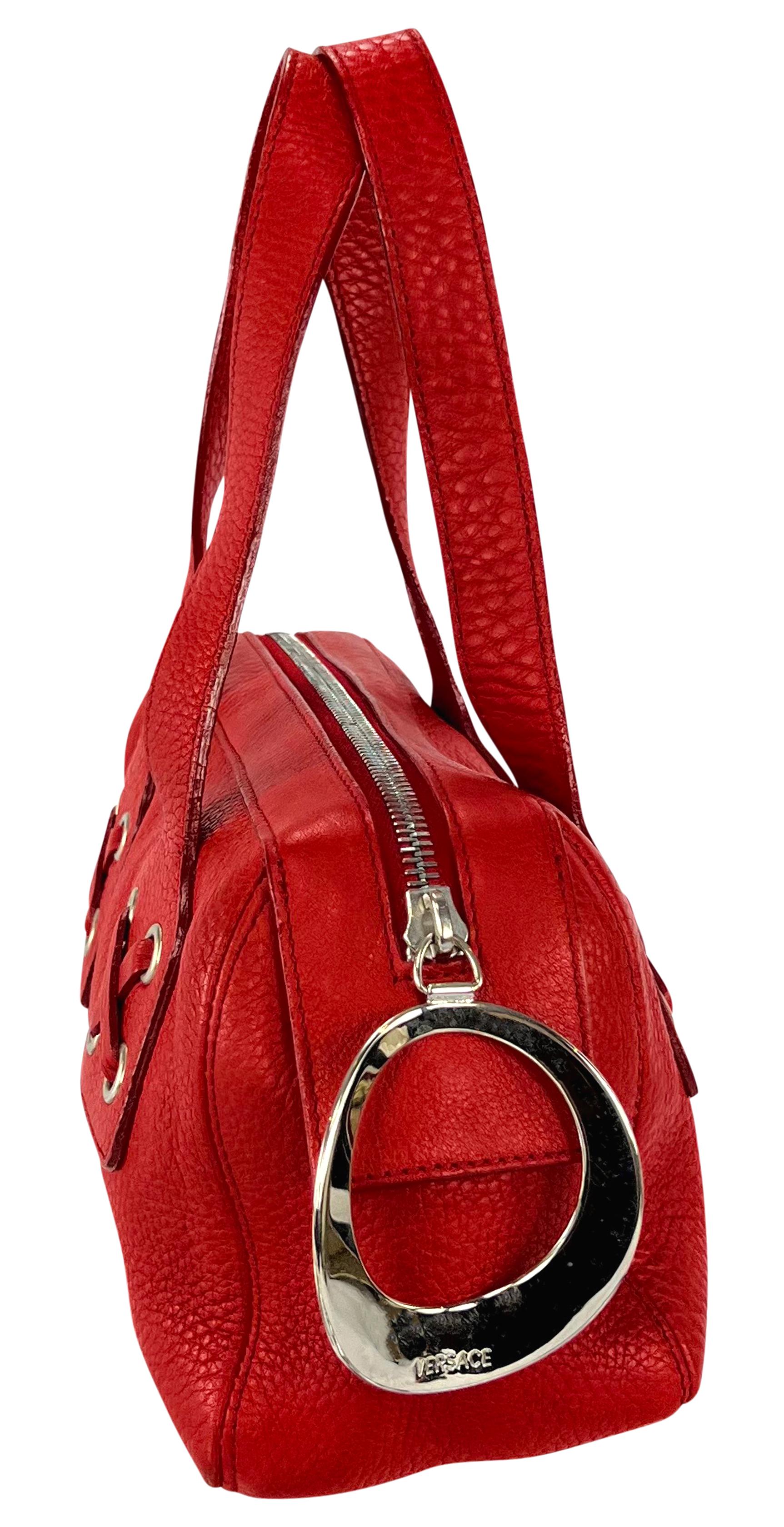 Donatella Versace designed this petite red leather bag for the Spring/Summer 2002 Gianni Versace collection. Made entirely of leather, this mini bag showcases a leather lace detail at the base of the handles and is finished with an exaggerated