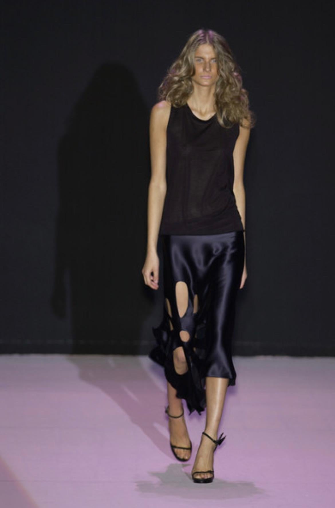 TheRealList presenta: una impresionante falda Gucci de seda negra, diseñada por Tom Ford. De la colección Primavera/Verano 2002, esta preciosa falda estilo pañuelo está confeccionada íntegramente en satén de seda negro y se completa con recortes