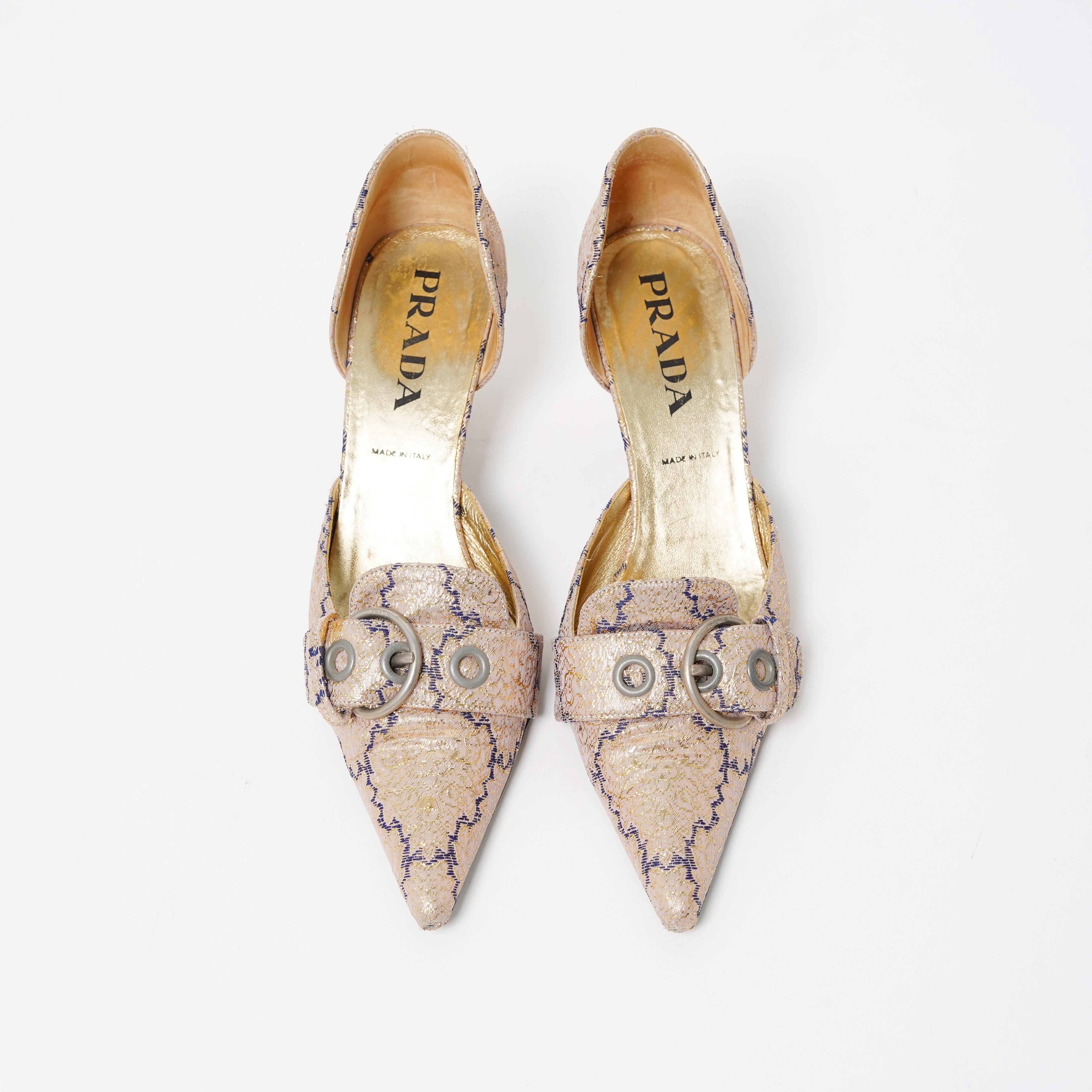 Voici une paire de talons Sabrina en lamé doré décoratif Prada S/S 2002 avec détails de boucles. La collection S/S 2002 était axée sur une nouvelle perspective du lamé - déconstruit et restructuré pour créer une image somptueuse mais sans excès.