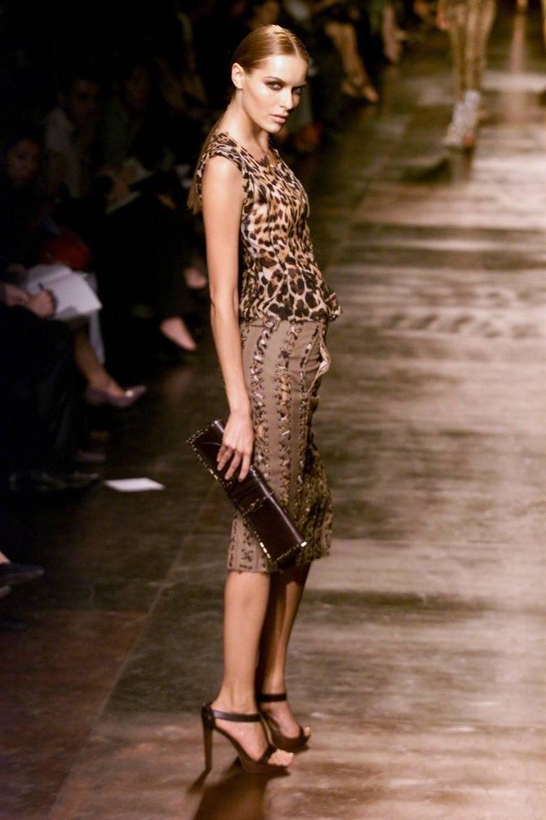 Ti presentiamo una pochette Yves Saint Laurent Rive Gauche in pelle traforata, disegnata da Tom Ford. Questa borsa è realizzata in pelle marrone intenso con inserti in bronzo invecchiato. Questa collezione è degna di nota perché è una delle