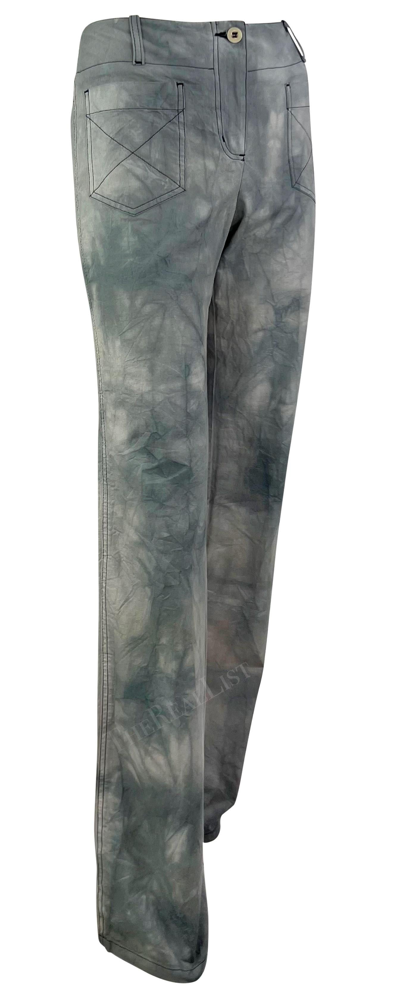 Présentation d'un pantalon gris tie-dye Chloé, dessiné par Phoebe Philo. Issu de la collection printemps/été 2003, ce pantalon gris est recouvert d'un imprimé tie-dye. Ce pantalon à jambe large présente un léger évasement et une taille haute.