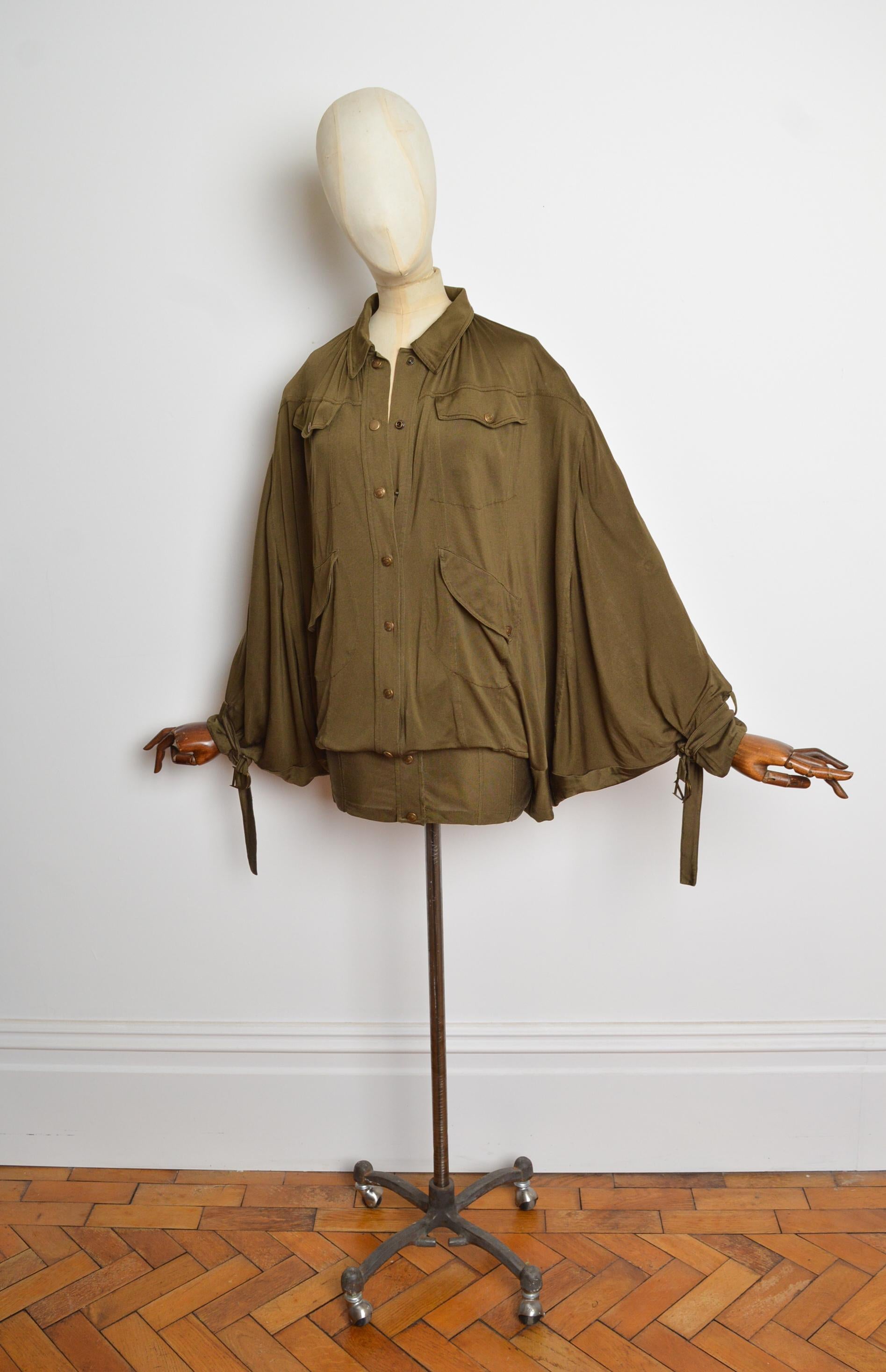 Sublime, Frühjahr/Sommer 2003 Khakigrünes Batwing-Kleid von John Galliano für Christian Dior. Mit langen Ärmeln mit dekorativen D-förmigen Schnallen an den Manschetten, Druckknopfverschluss in Antikbronze, Batwing-Fallschirmsilhouette und minilangem