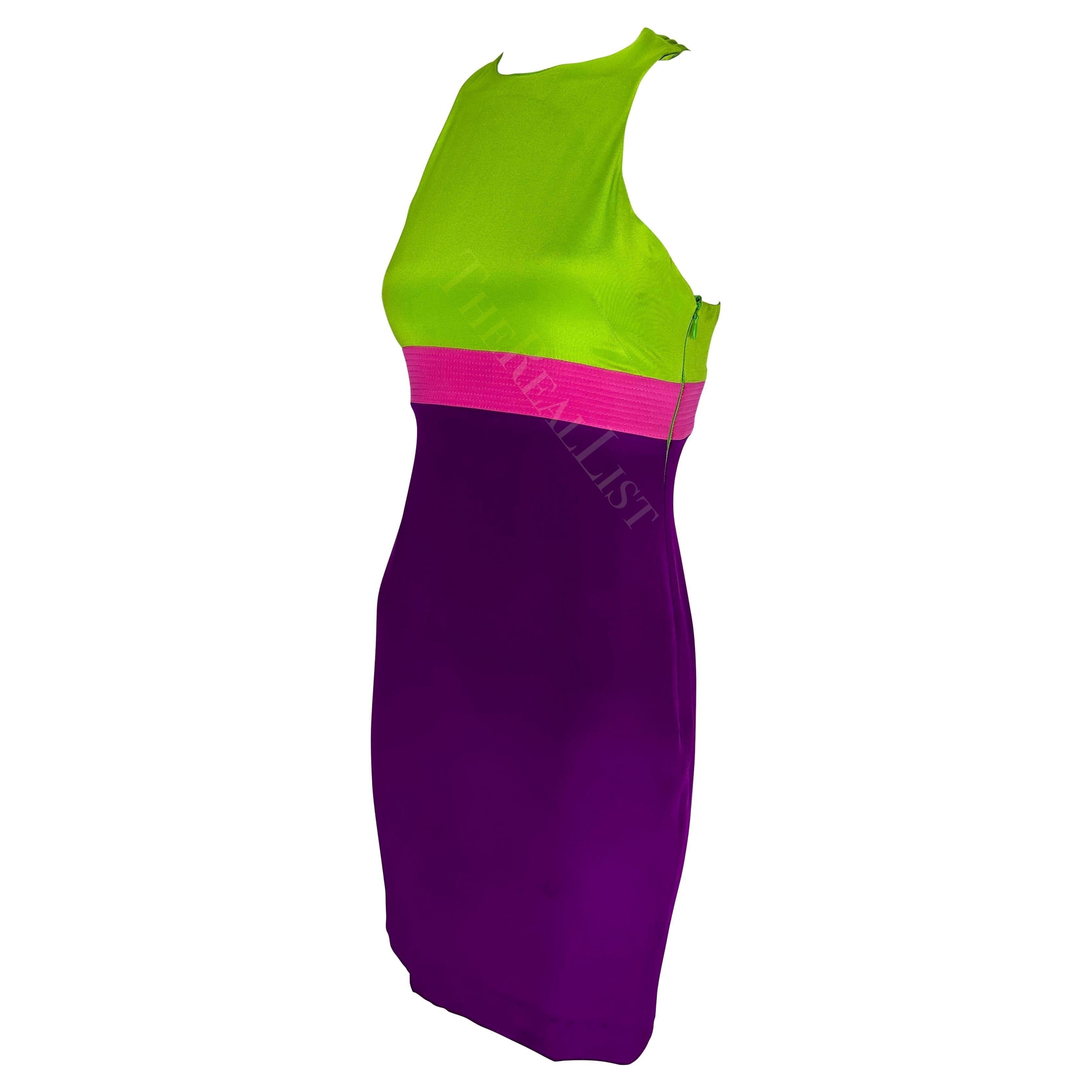 Ti presentiamo un mini abito di Gianni Versace viola e verde, disegnato da Donatella Versace. Dalla collezione primavera/estate 2003, questo abito a blocchi di colore iper-girale presenta un top verde, una gonna viola e una fascia rosa acceso sotto