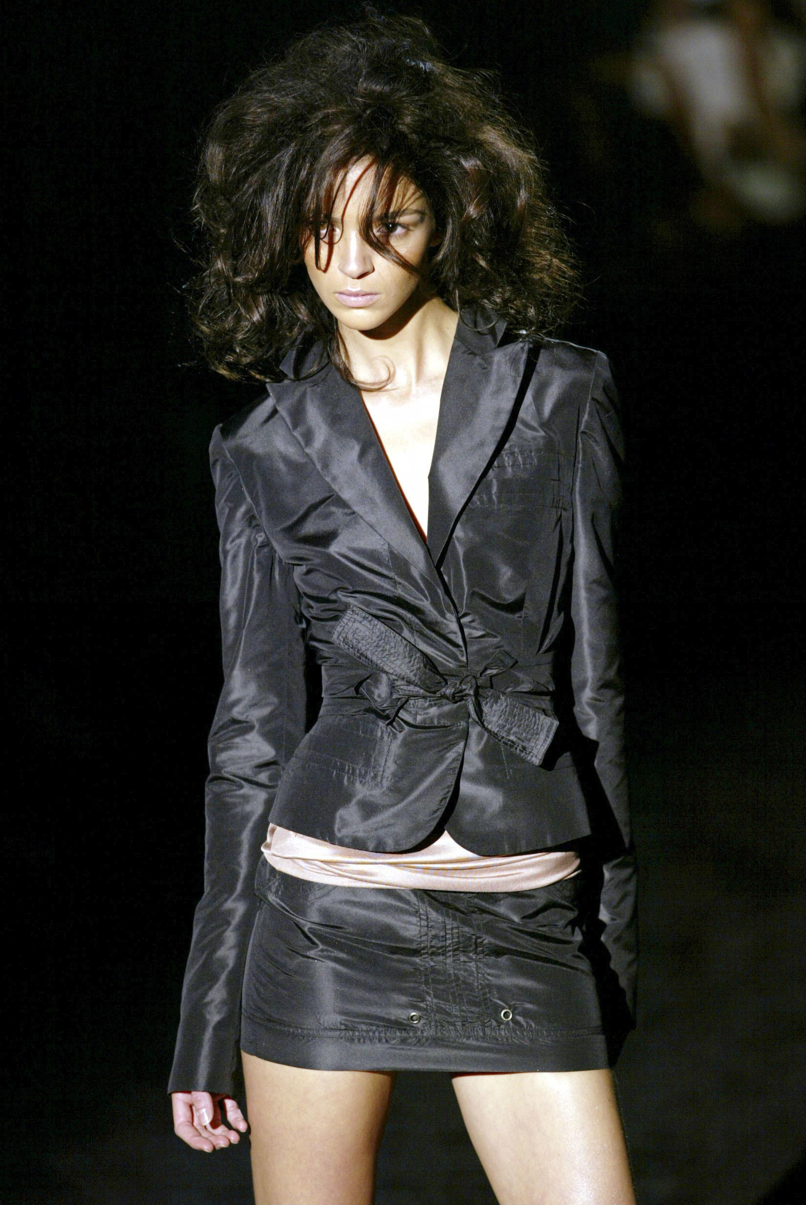From Tom Ford’s Spring/Summer 2003 Gucci collection, this black mini skirt is crafted in structured cotton twill with tonal topstitching. The design features front pockets with an emroidered design, silver-tone grommet details at the hem, and a wide