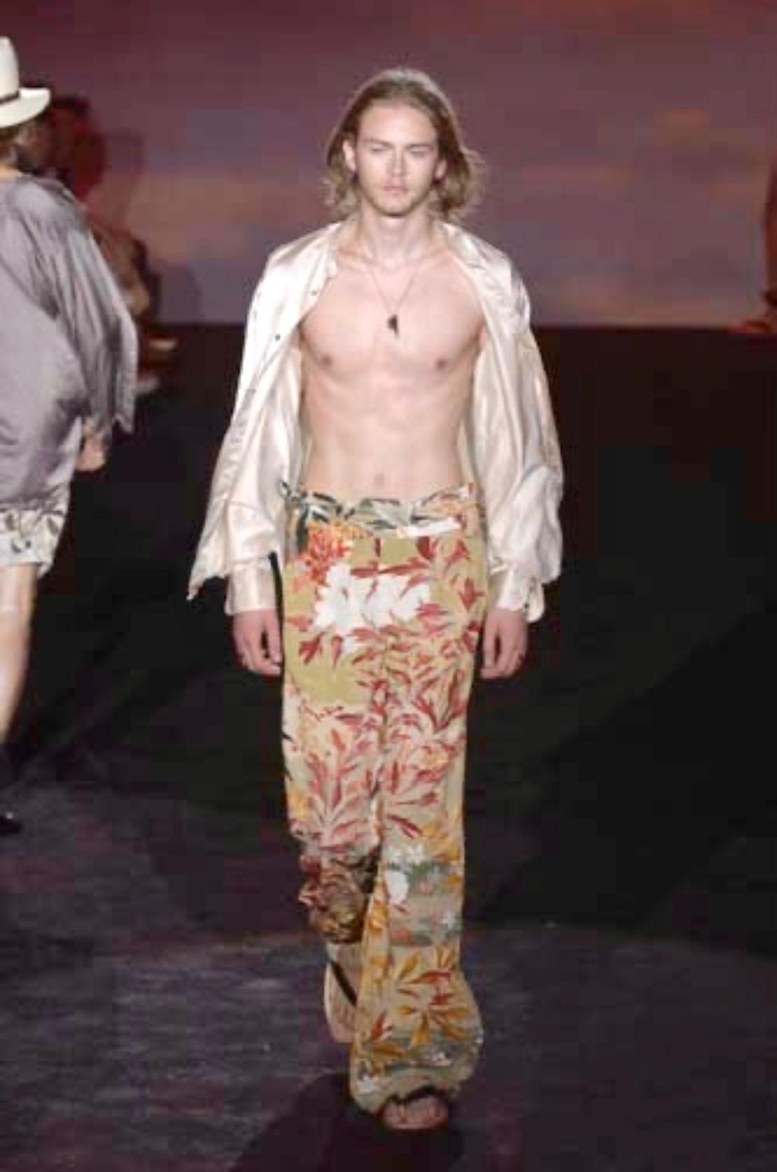 Wir präsentieren eine grüne, geblümte Gucci-Hose, entworfen von Tom Ford. Dieser Druck aus der von der Chinoiserie inspirierten Frühjahr/Sommer-Kollektion 2003 wurde erstmals auf dem Laufsteg für Männer gezeigt und zeigt große bunte Lotusblumen. Die