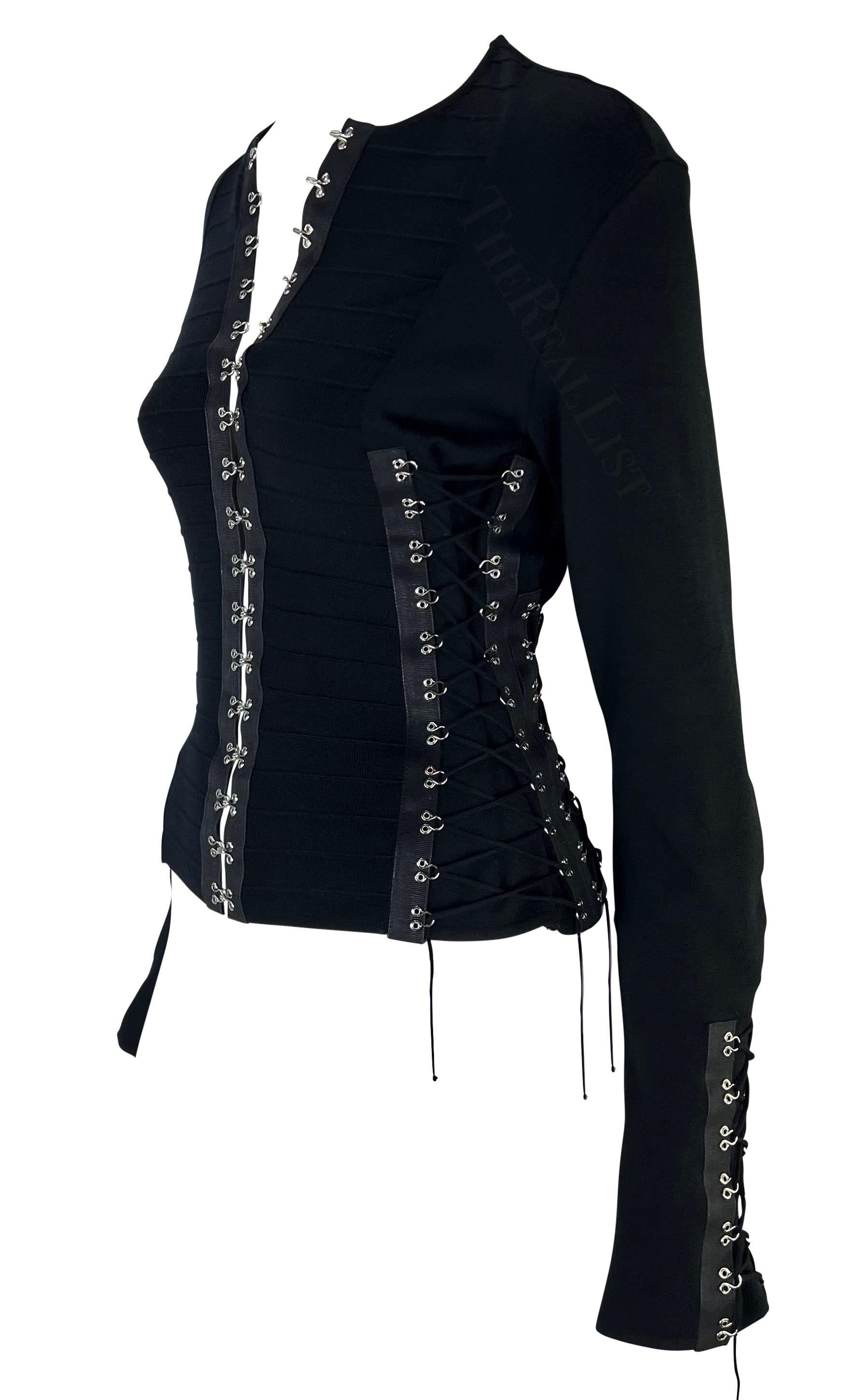 Presenting an incredible black hook and eye knit John Galliano cardigan. From his Spring/Summer 2003 collection, this fabulous form-fitting sweater features hook and eye closures at the front closure with lace-up details around the torso and at the