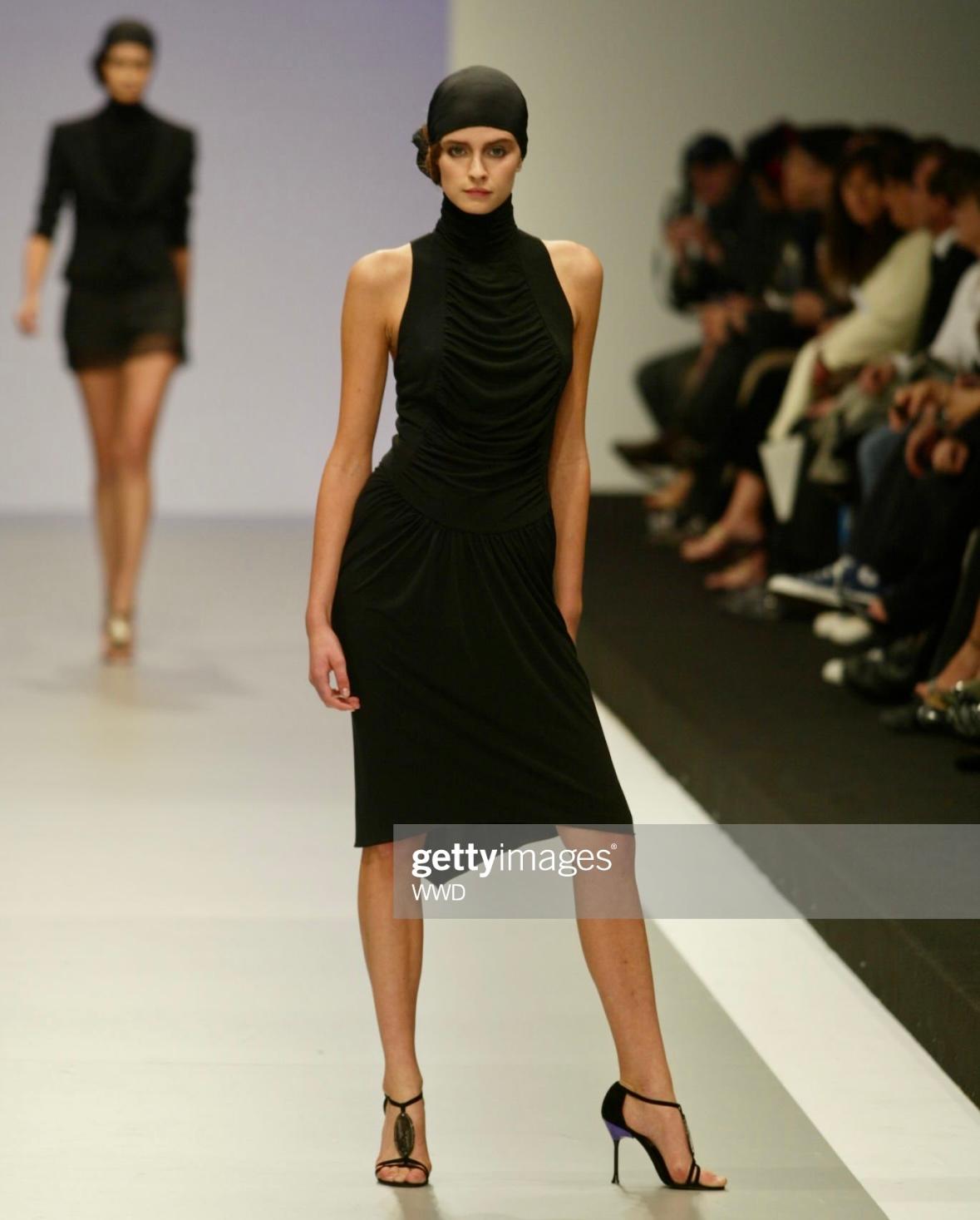 Presenting a chic black halterneck Karl Lagerfeld midi dress. From his Spring/Summer 2003 ready-to-wear collection, this dress debuted on the season's runway. Featuring a mock neck, draping at the front, and exposed back, this vintage runway dress