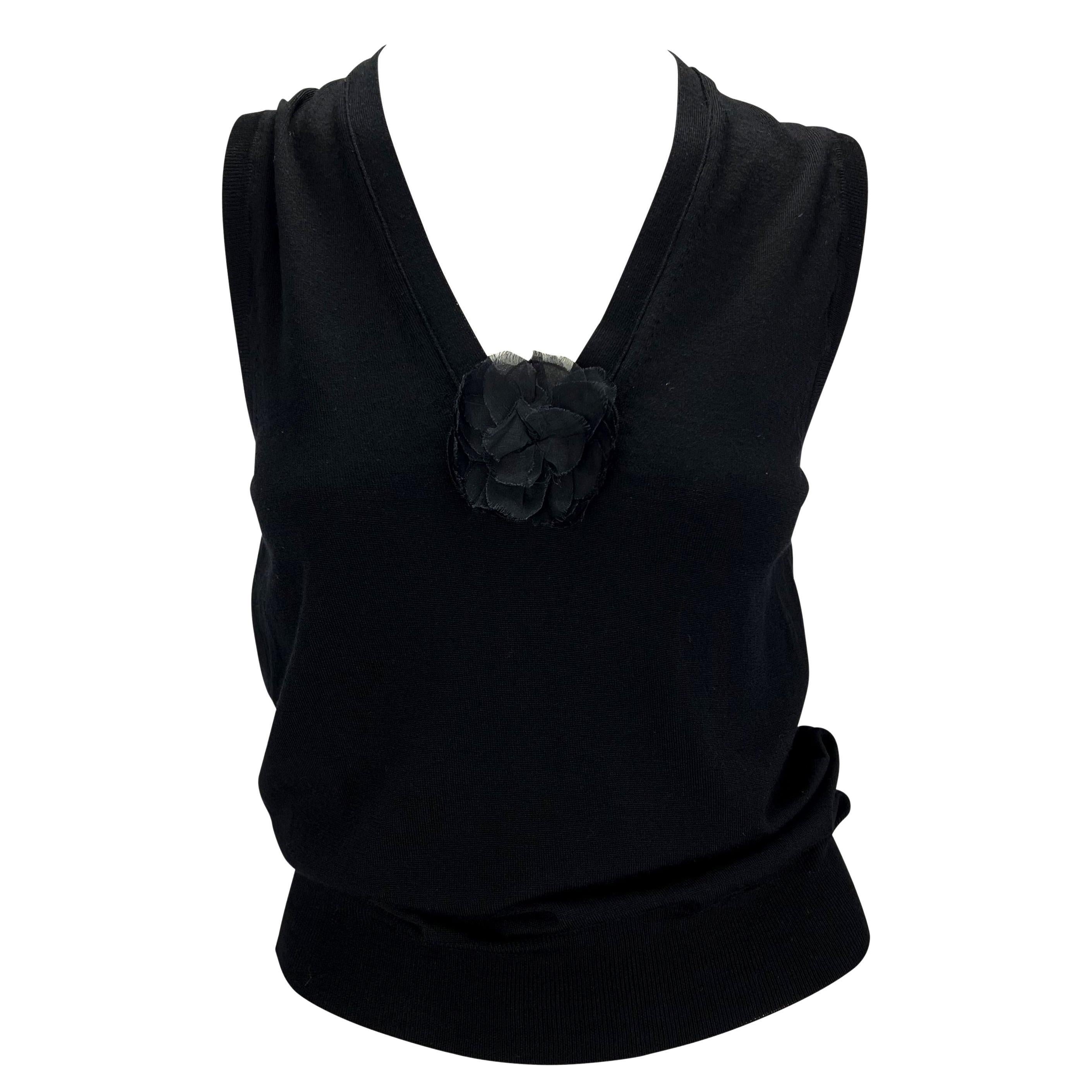 TheRealList presents: a black wool sweater vest designed by Tom Ford for Yves Saint Laurent Rive Gauche's Spring/Summer 2003 collection. This stretchy, semi-sheer piece features a chiffon flower appliqué at the bust, accenting the v-shaped neckline.