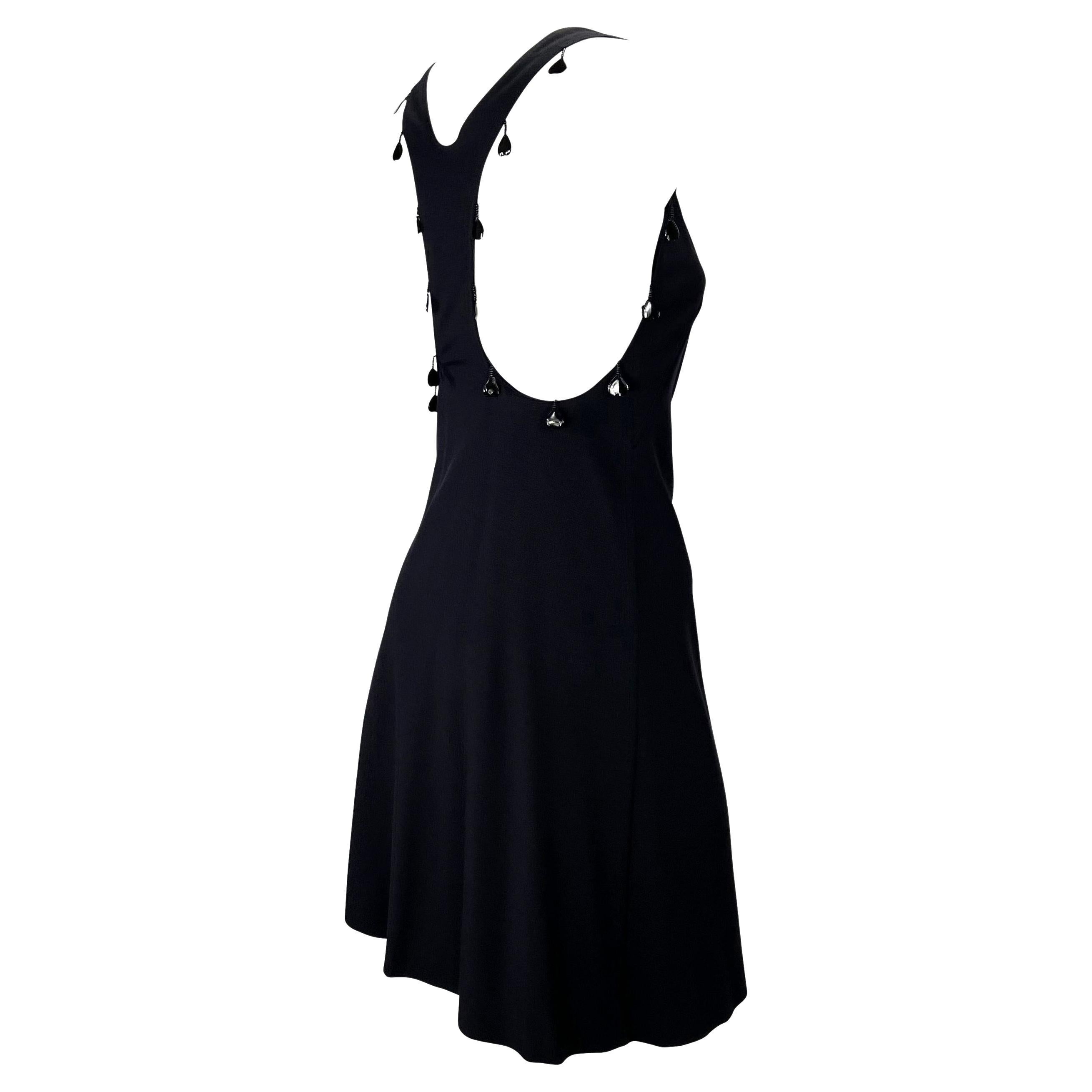 Présentation d'une robe noire en maille dos nageur Chloé, dessinée par Phoebe Philo. Issue de la collection printemps/été 2004, cette magnifique petite robe noire présente une encolure dégagée, un dos nageur, une jupe évasée et est agrémentée de