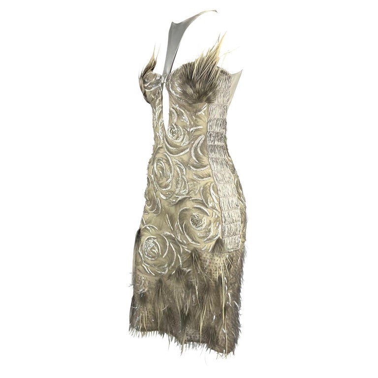 TheRealList presents: an incredible silver beaded Gucci dress, designed by Tom Ford. From the Spring/Summer 2004 collection, this absolutely stunning dress is covered in hand sewn beads which create an abstract rose pattern. Feathers at the bottom