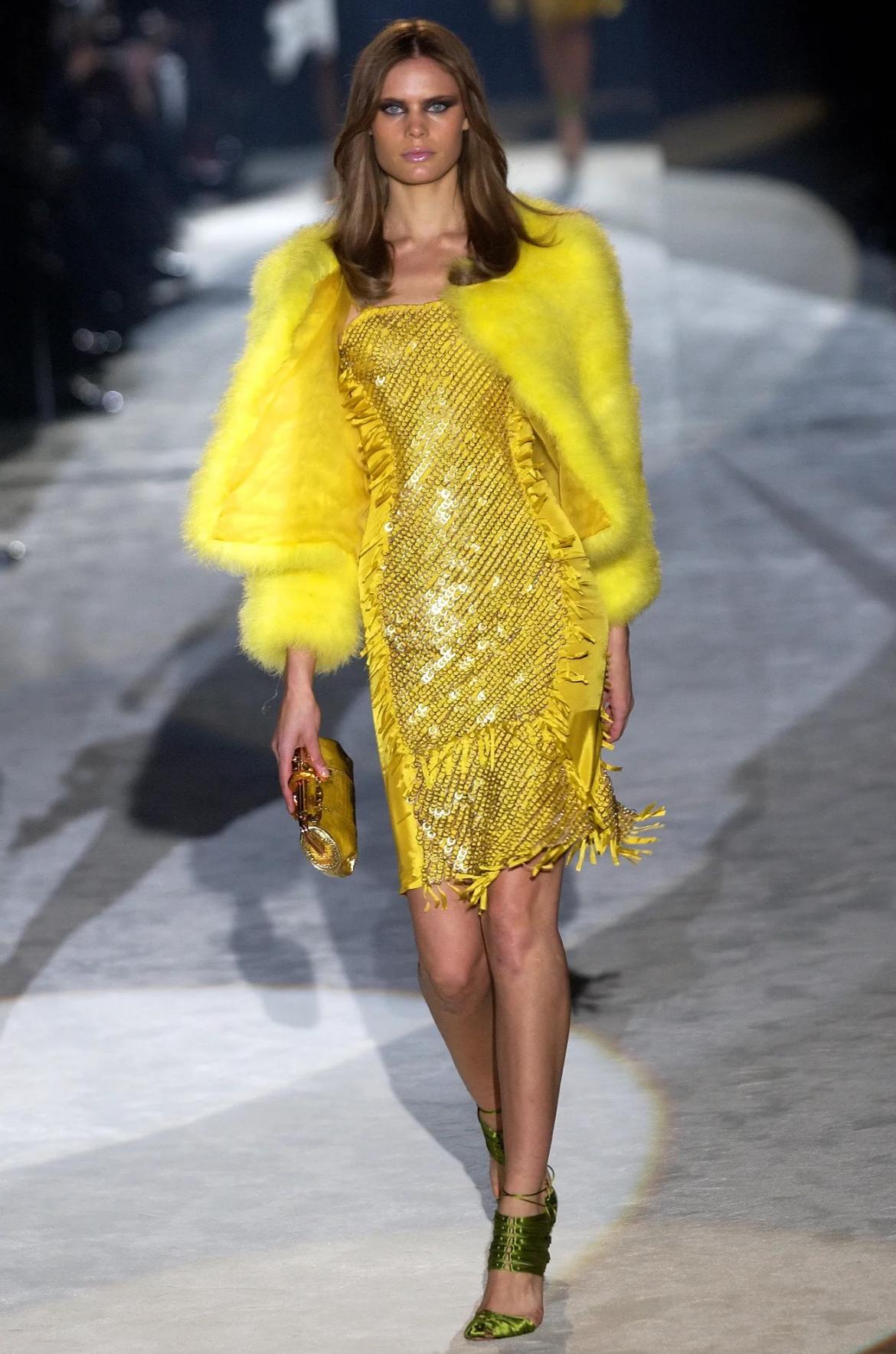 Issue de la collection printemps/été 2004 de Gucci par Tom Ford, cette mini robe bustier jaune a fait ses débuts sur le podium en tant que look 31, portée par Adina Fohlin. La silhouette audacieuse présente une base ajustée en satin recouverte