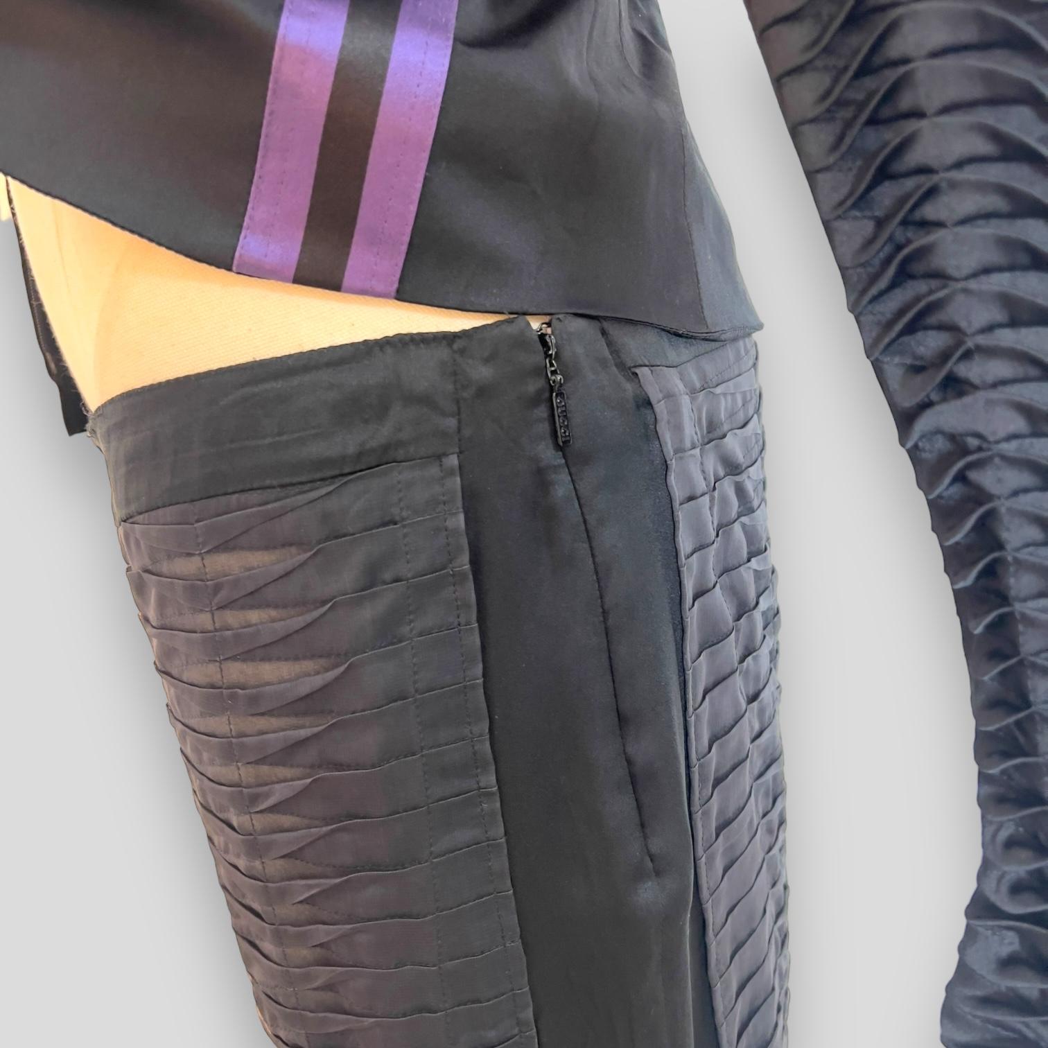 Ti presentiamo una splendida giacca Gucci in seta nera plissettata, un capolavoro disegnato da Tom Ford. Questo splendido pezzo proviene dalla collezione Primavera/Estate 2004 e ha fatto il suo debutto in passerella come look 17, indossato dalla