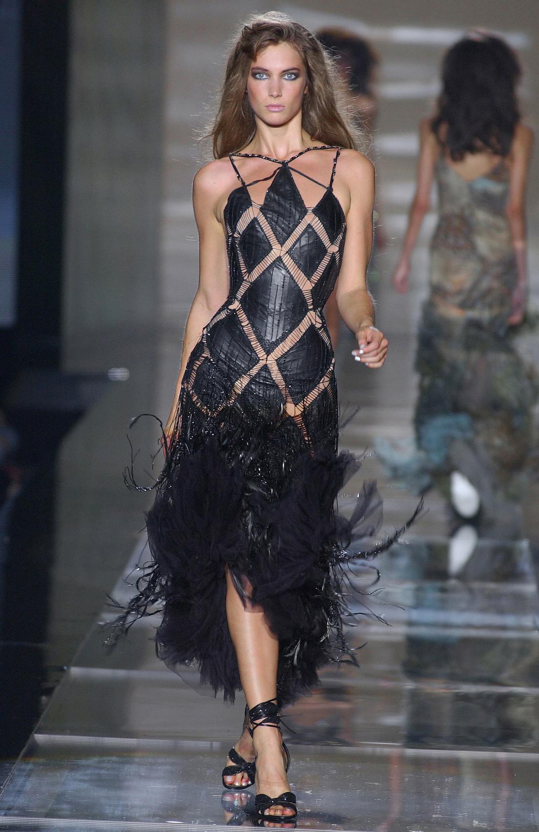 S/S 2004 Roberto Cavalli geometric black embellished leather cutout corset fringe dress. Hyper-fitted sleeveless dress with shoestring stamped lace-up corset back and geometric black leather paneling throughout upper, with long silk chiffon and