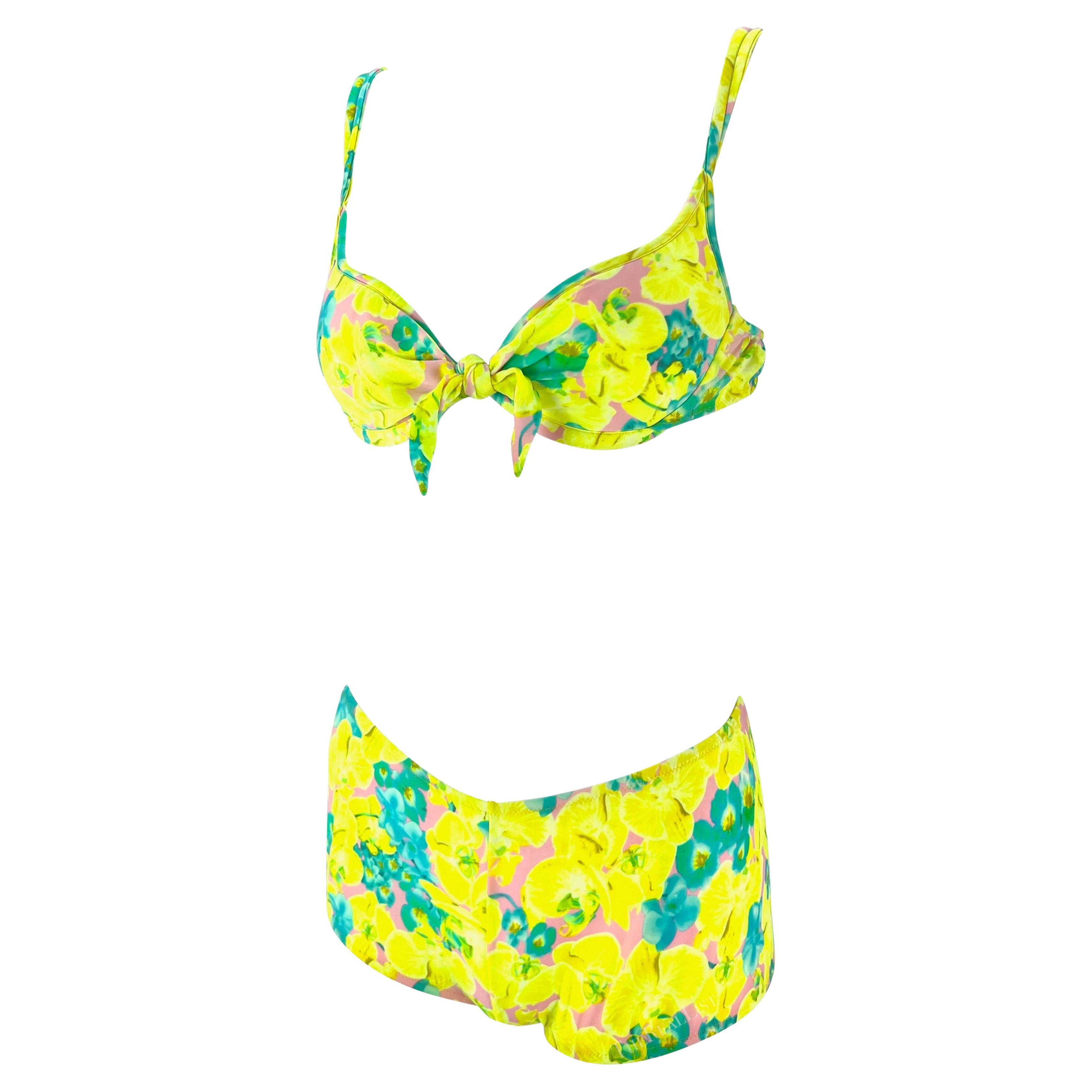 Presenting a vibrant yellow floral Versace bikini set, designed by Donatella Versace. From the Spring/Summer 2004 collection, this bikini set is comprised of a plunge-style top and boyshorts both covered in a bright orchid print. The top is made