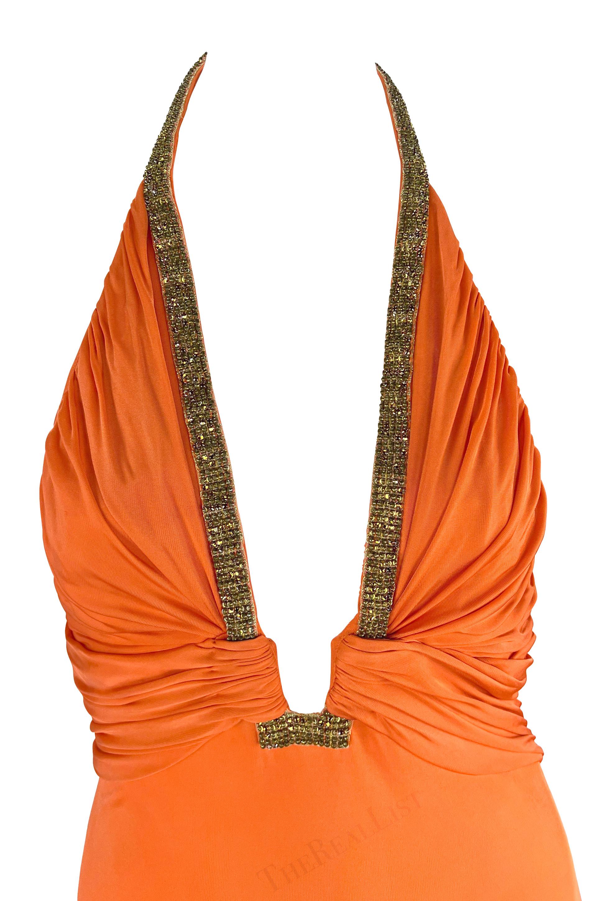 This beautiful orange Roberto Cavalli halterneck gown from the Spring/Summer 2005 collection features ruching gathered at the plunging neckline, highlighted by intricate brassy sequins interspersed with amber rhinestones. The viscose blend fabric