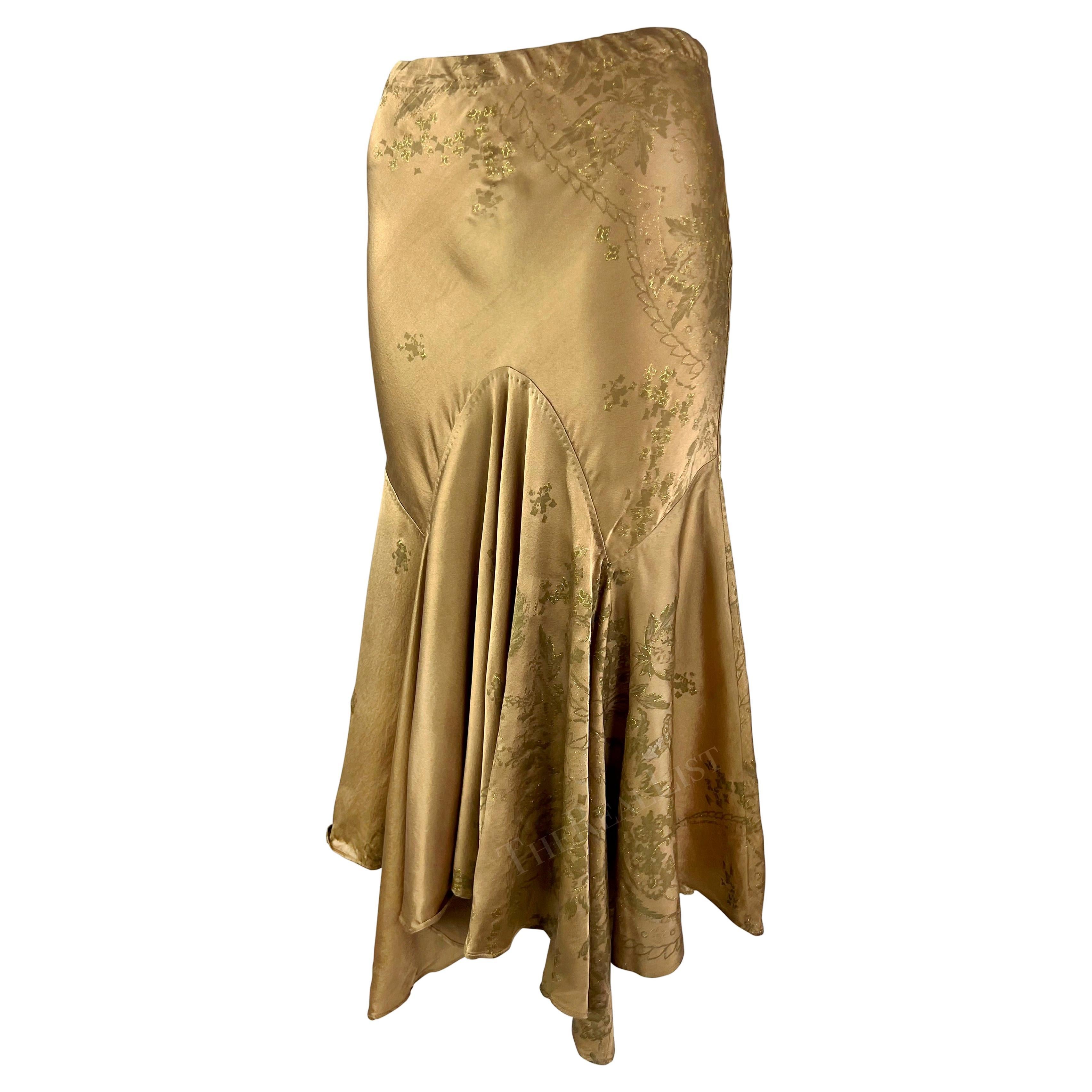 Voici une fabuleuse jupe de style mouchoir en soie dorée de Roberto Cavalli, issue de la collection printemps-été 2005. Cette jupe scintillante aux tons dorés est entièrement réalisée en soie luxueuse. La jupe au genou est recouverte d'un motif