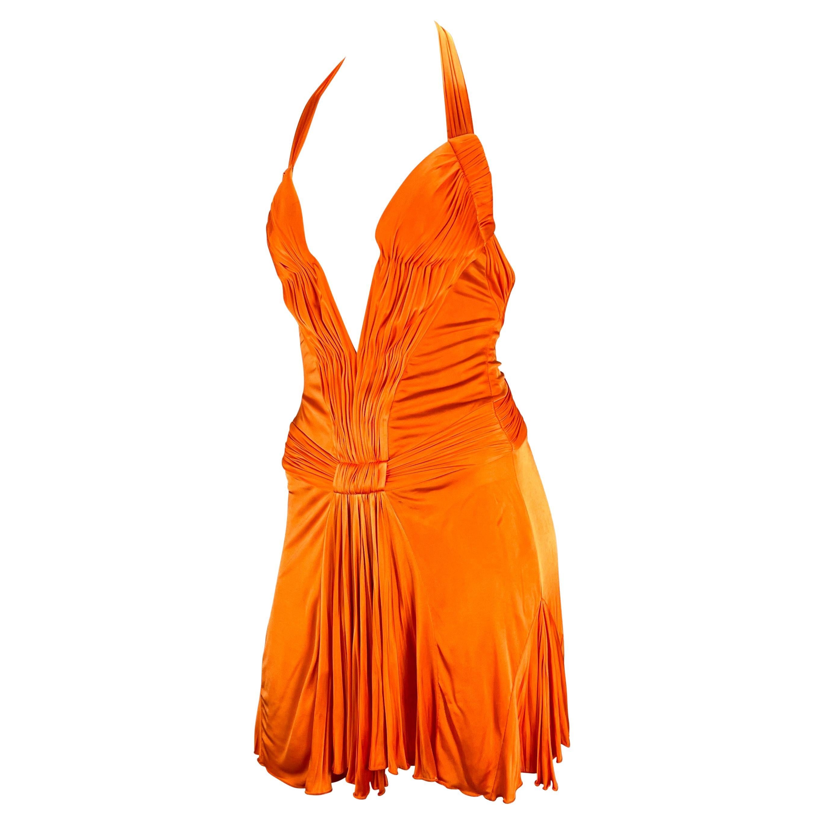 Sie präsentiert ein leuchtend orangefarbenes, tief ausgeschnittenes Minikleid von Roberto Cavalli. Dieses schöne und lebhafte Kleid aus der Frühjahr/Sommer-Kollektion 2005 zeichnet sich durch einen tiefen Ausschnitt, einen halboffenen Rücken und