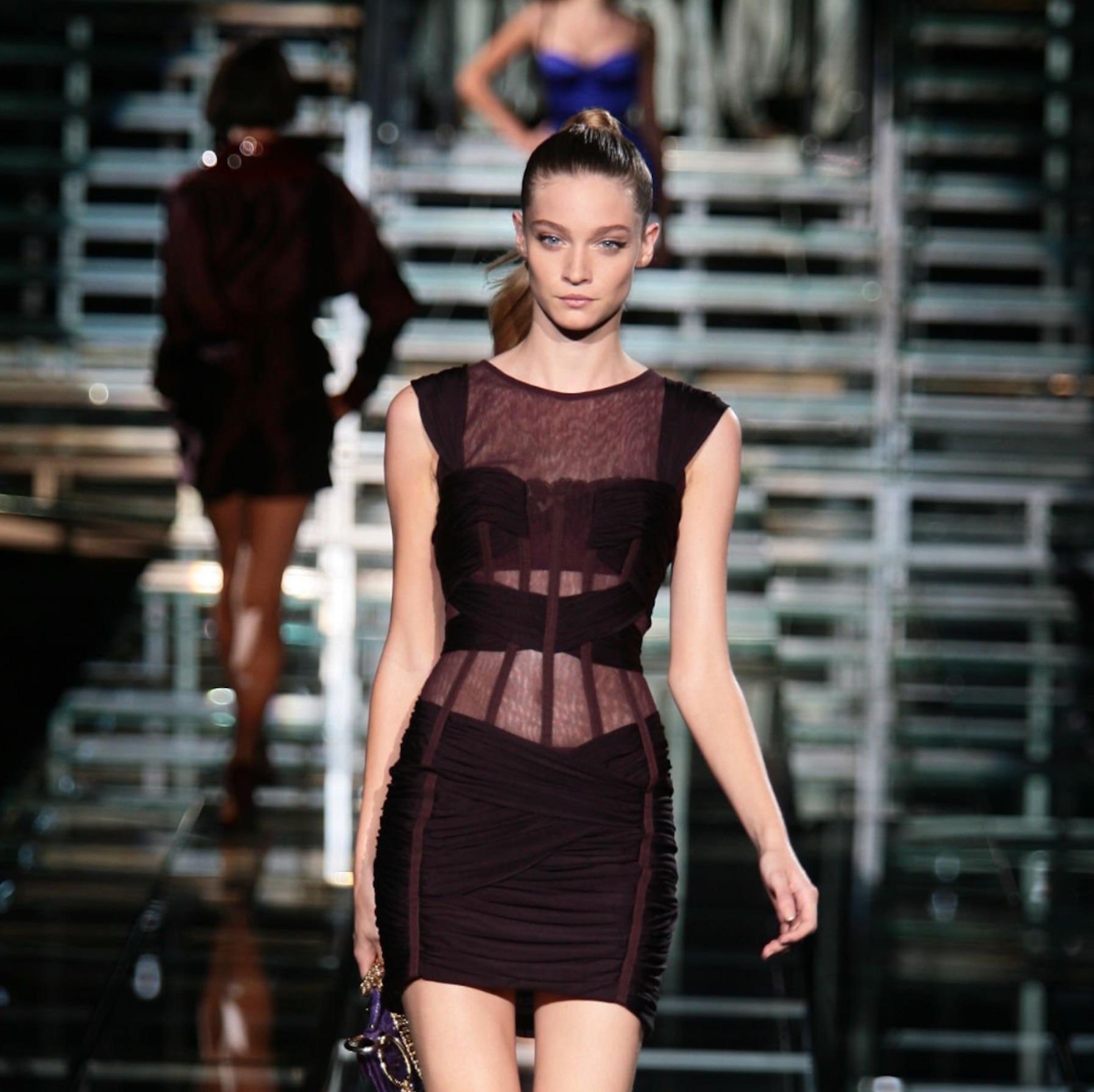 Dalla collezione Primavera/Estate 2007 di Dolce & Gabbana, questo miniabito bordeaux è realizzato in tulle elasticizzato e presenta una scultorea costruzione a corsetto. La silhouette aderente è accentuata da un intricato drappeggio increspato e da