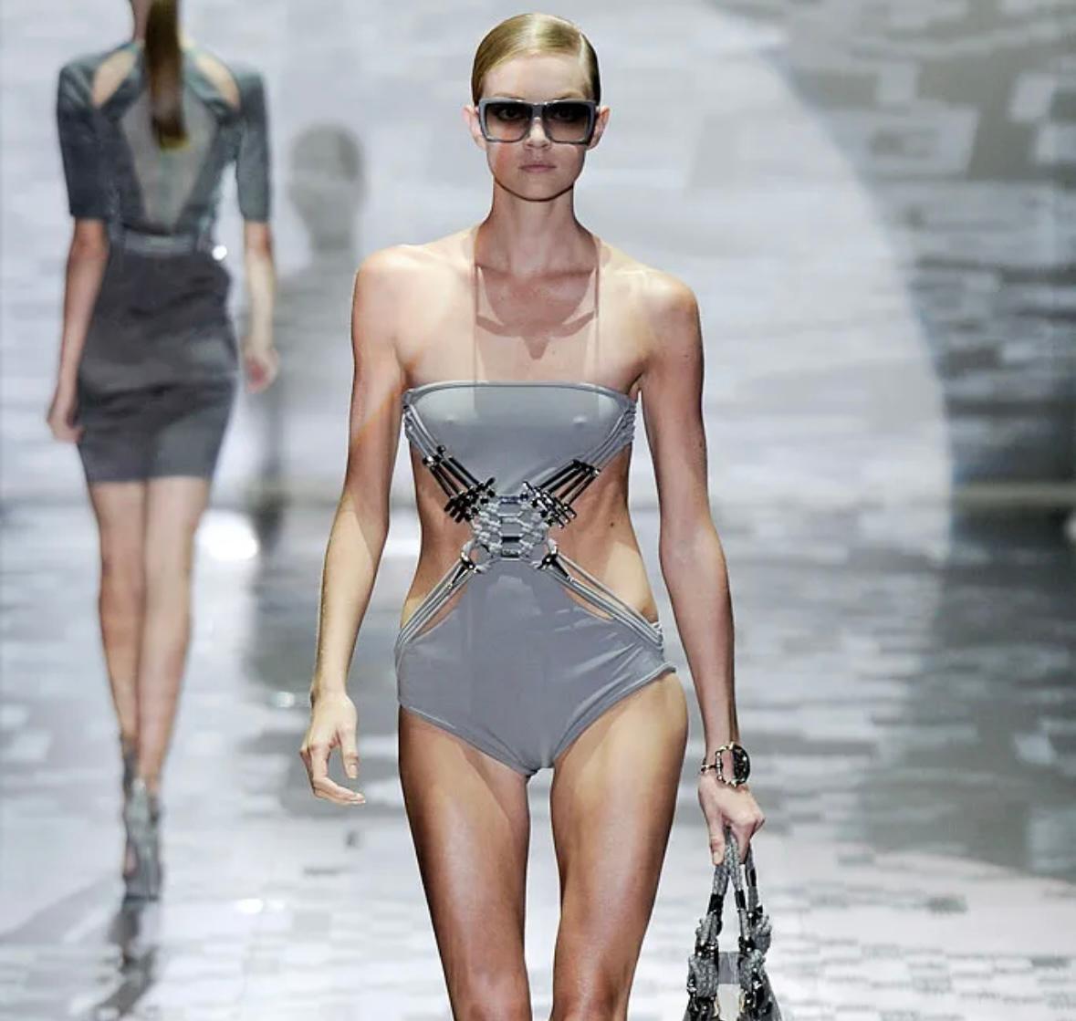 Ti presentiamo un futuristico costume da bagno intero grigio della collezione Primavera/Estate 2010 di Gucci, disegnato da Frida Giannini. Questo pezzo scultoreo ha debuttato sulla passerella della stagione come look 13 ed è stato anche messo in
