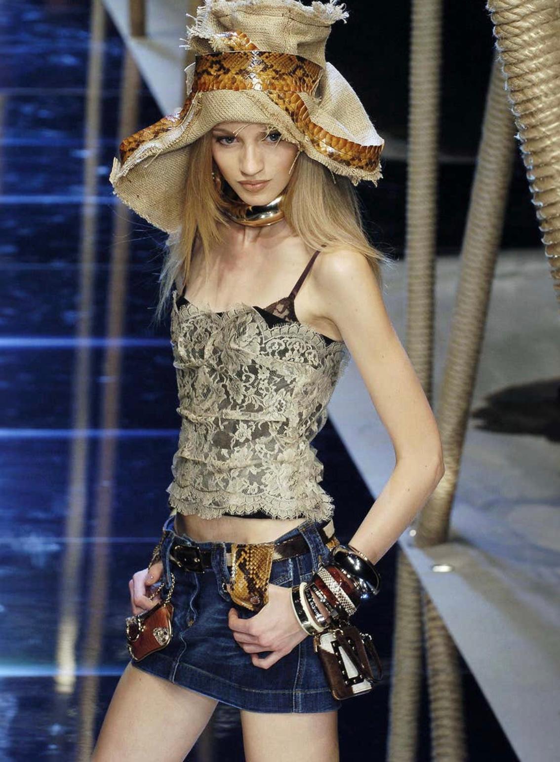 Este exquisito corsé Dolce & Gabbana 2005 encarna la elegancia atemporal y la artesanía italiana. Confeccionado en delicado encaje floral, presenta una silueta estructurada con un escote sin tirantes que resalta sus intrincados detalles y su lujosa