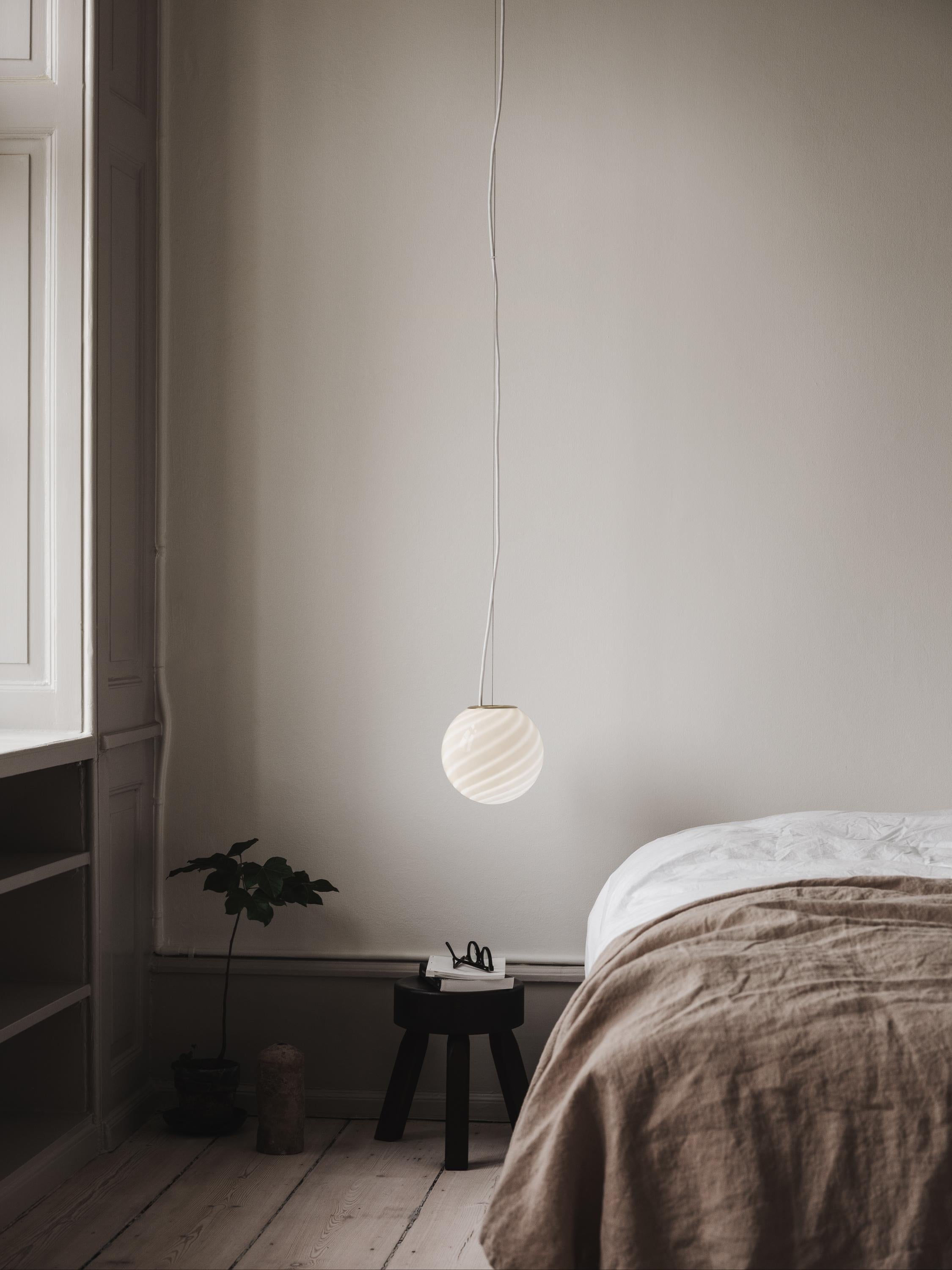 Sphere-shaped pendant ceiling lamp crafted from mouth-blown opaline glass. The design features a swirl pattern obtained using an original 1970s mould, specifically picked to give the lamp a clean expression. The piece includes a hand-casted fitting