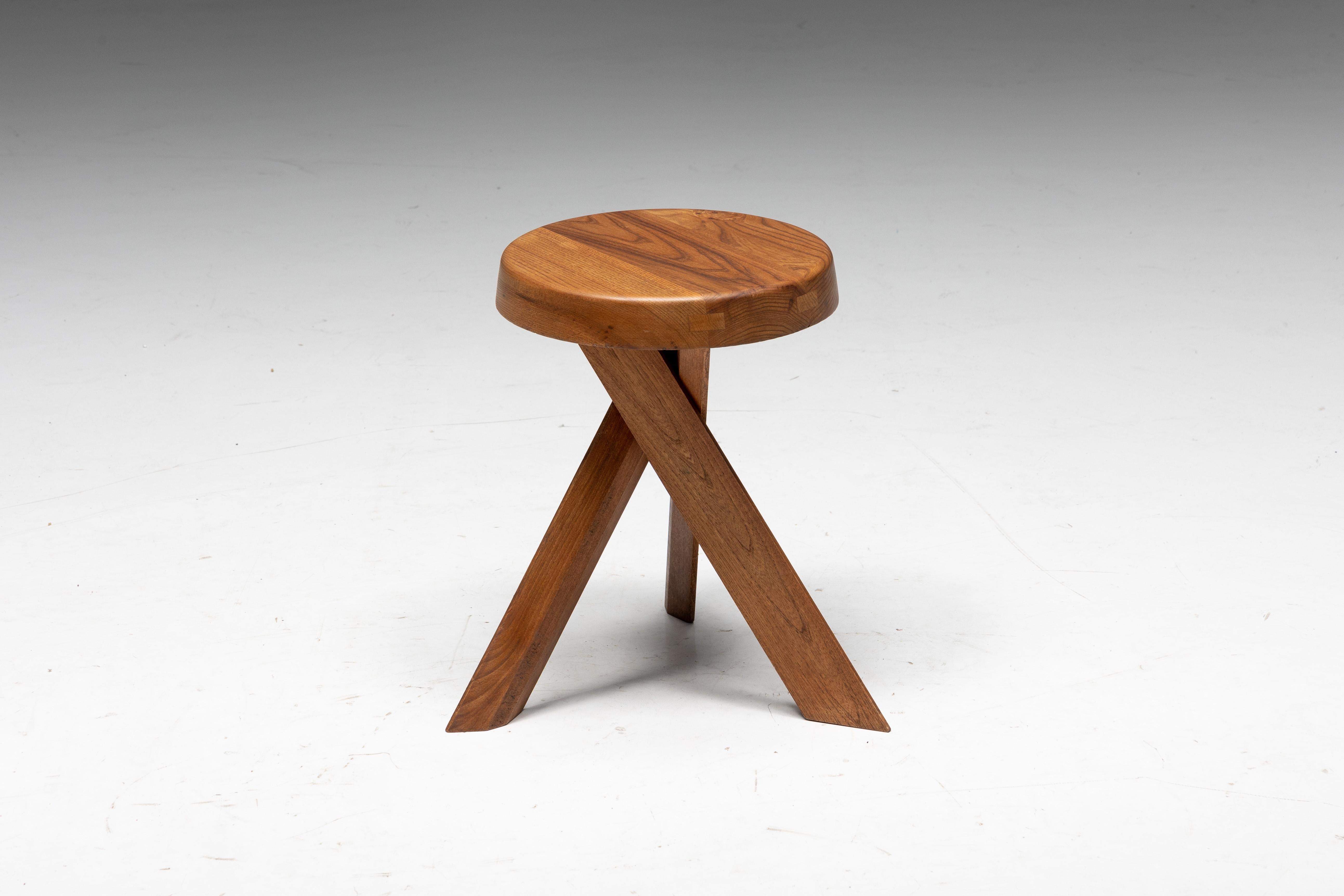 Early edition stools by Pierre Chapo, meticulously crafted from solid elm wood in 1970s France, feature a thick seating with natural veining and three crossed feet. Visible joints along the seating's edge are typical of Pierre Chapo's creations. The