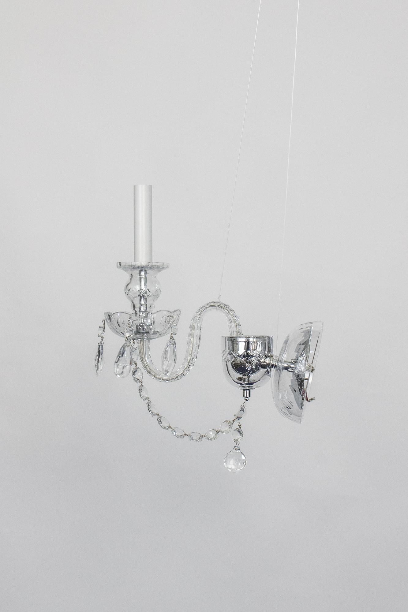 A pair of single arm crystal sconces, traditional crystal arms, bobeche, and backplate. Chrome plated metals. Made by Preciosa in the Czech Republic. New, showroom sample. Wired for use in the US, 40 watt max.